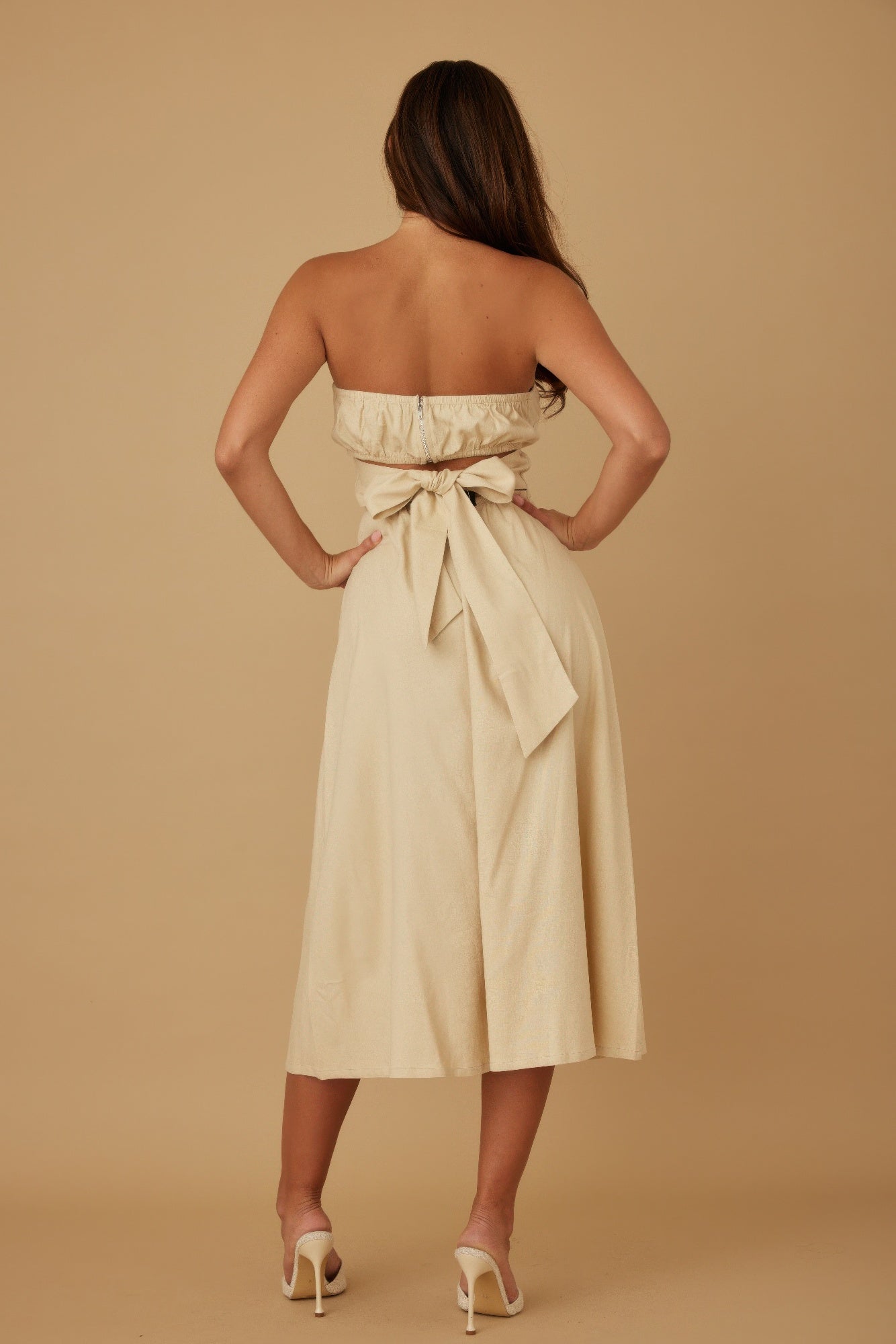 Back view of ivory strapless linen midi dress with tied bow detail
