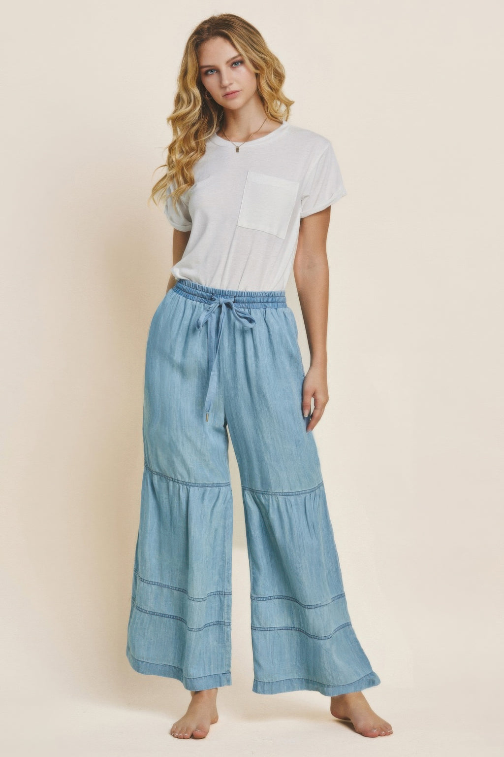 Washed denim tiered wide-leg pants in light blue with elastic waistband and drawstring