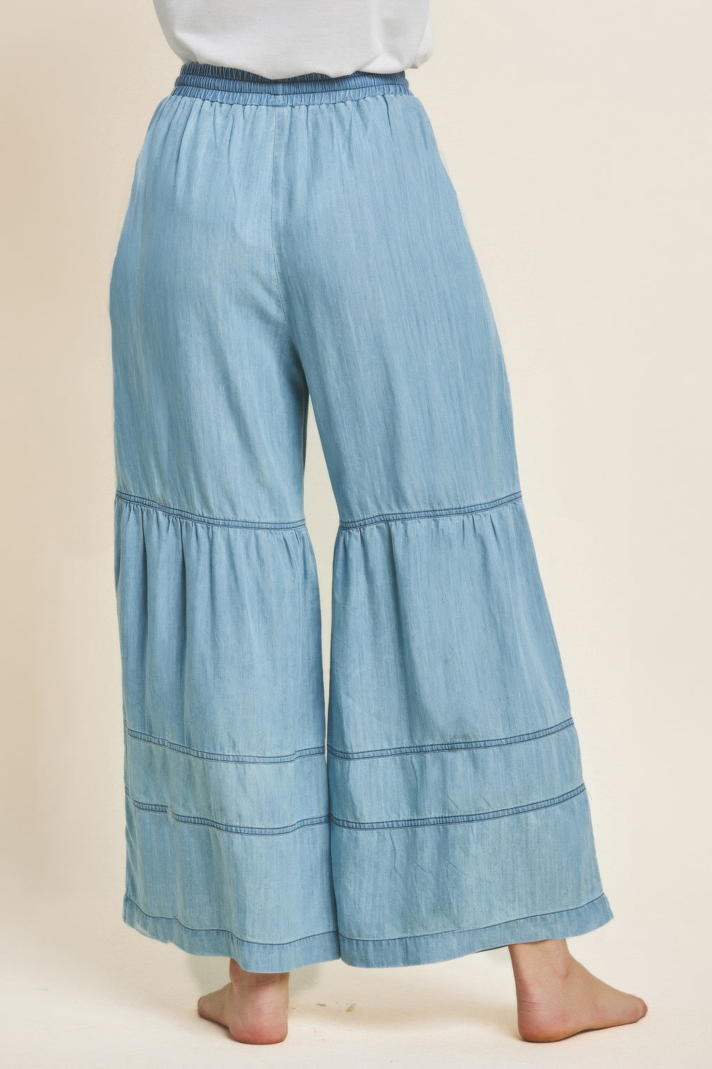 Light-blue washed denim tiered wide-leg pants with tiered hem panels and elastic waist