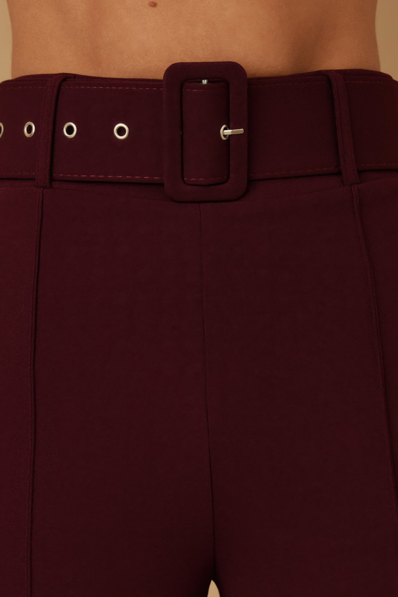 Close-up: wine buckle belt with metal loop details on high-waist pants.