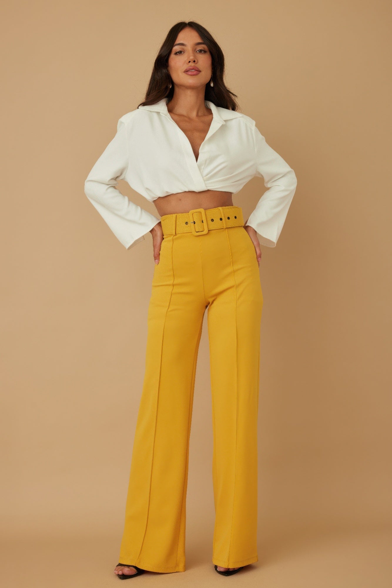 High-waist mustard pants with buckle belt and wide straight legs.