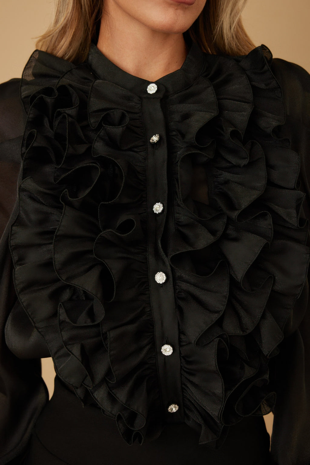 Black ruffle micro crystal blouse neckline close-up with stacked fabric ruffles and shiny buttons.