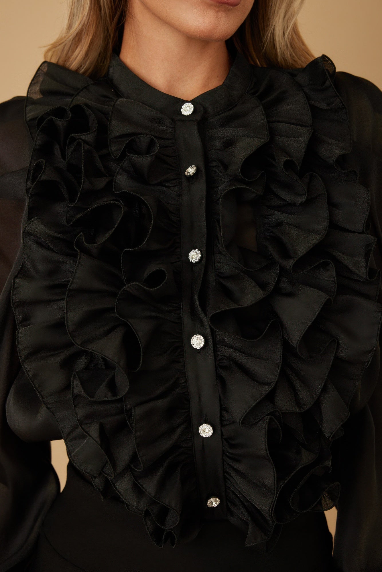 Black ruffle micro crystal blouse neckline close-up with stacked fabric ruffles and shiny buttons.