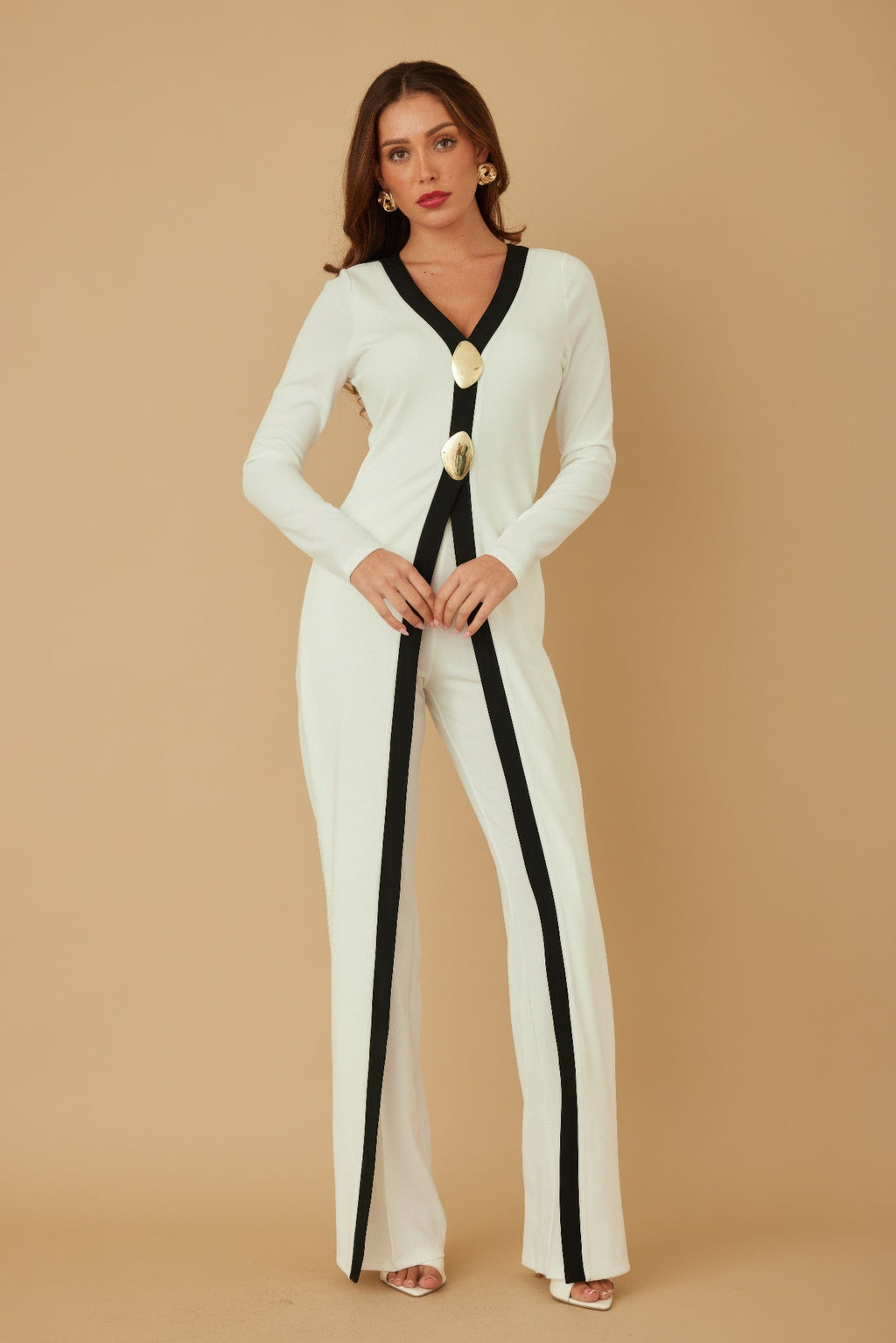 Front view long cream jumpsuit with black trim stripe, V-neck, and two oval mirror-stone buttons
