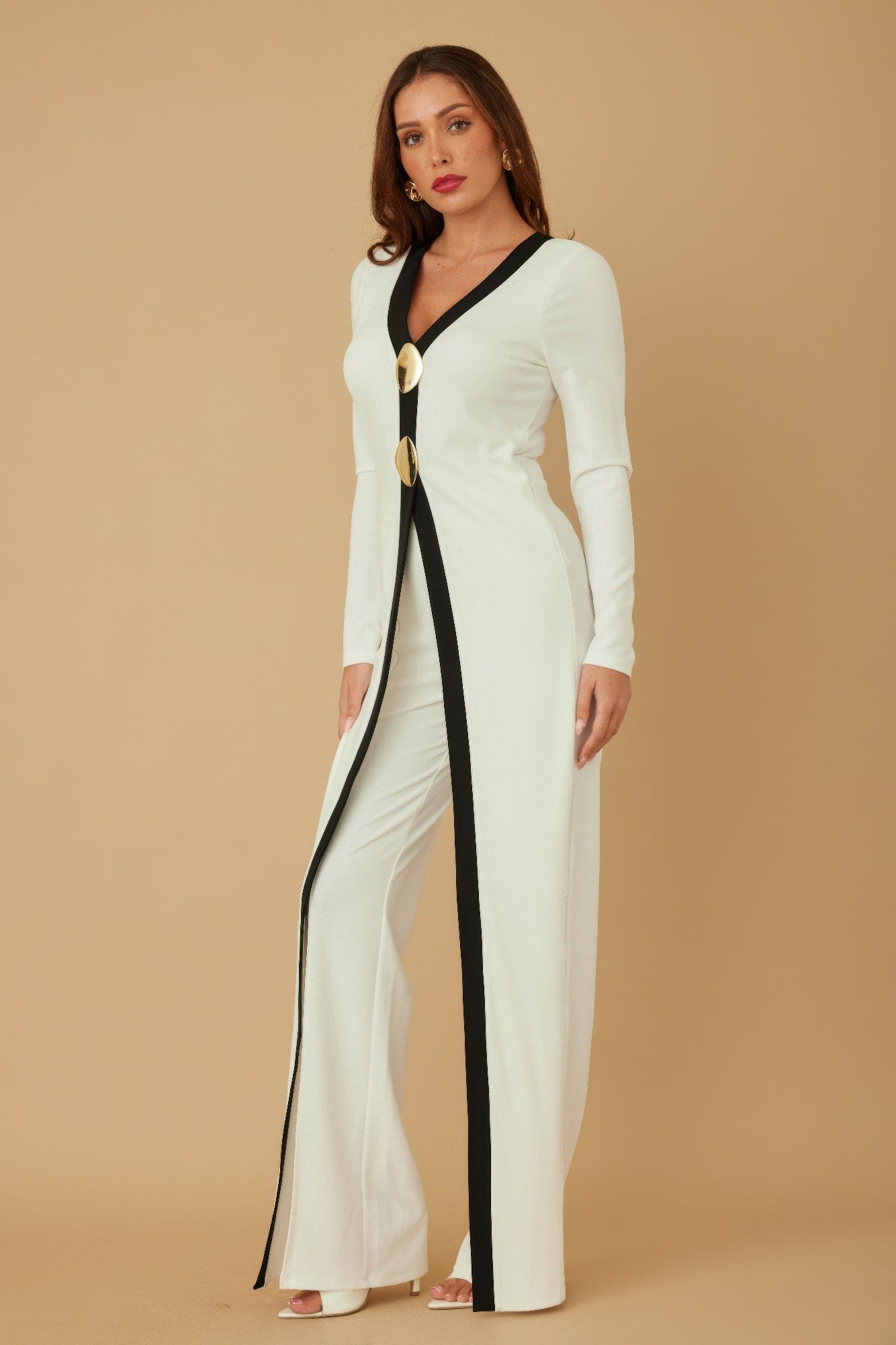 Cream long jumpsuit with black front stripe, V-neck, long sleeves, and gold mirror-stone buttons