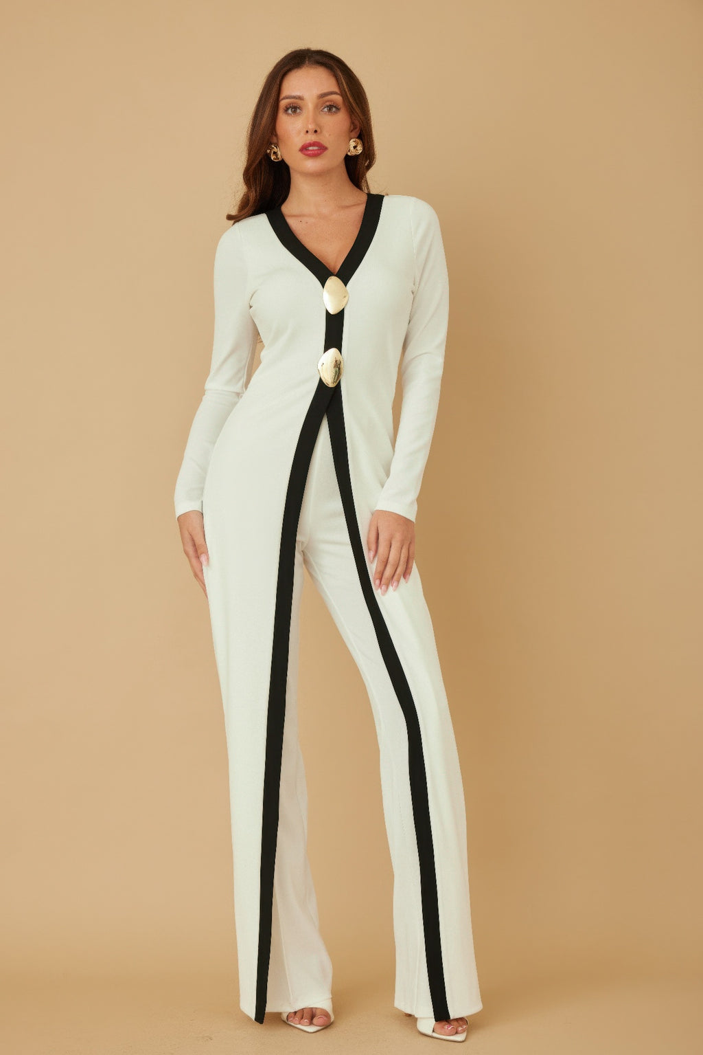 Side view cream long jumpsuit with black trim panel and two gold oval mirror-stone buttons