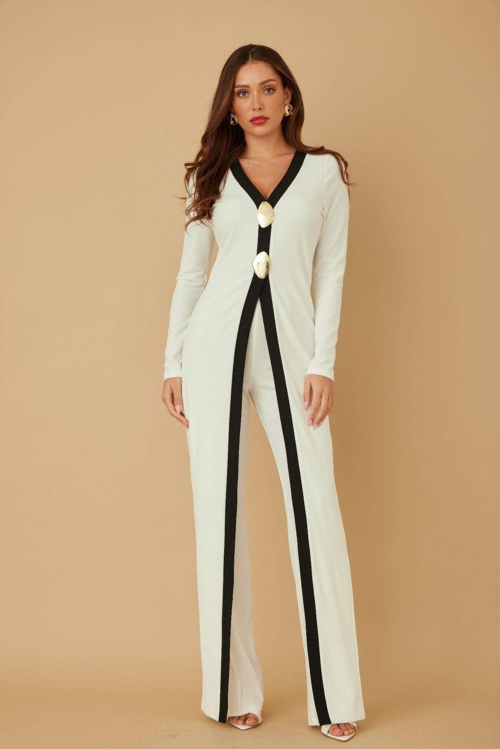 Full-length cream jumpsuit with black V-neck trim and gold oval mirror-stone accents on front