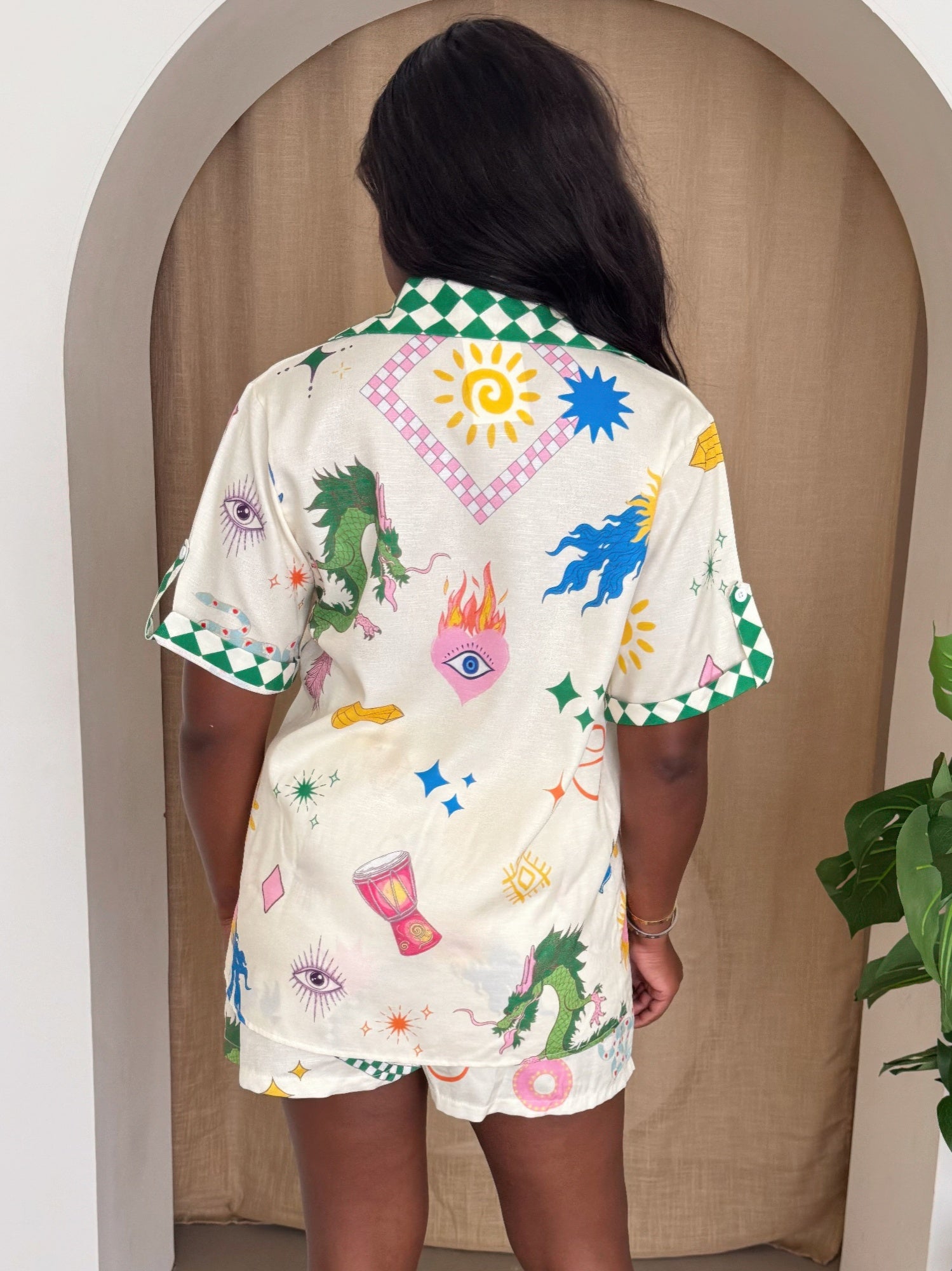 Dragon Dreams short set—back view: cream shirt with green trim and colorful motif prints