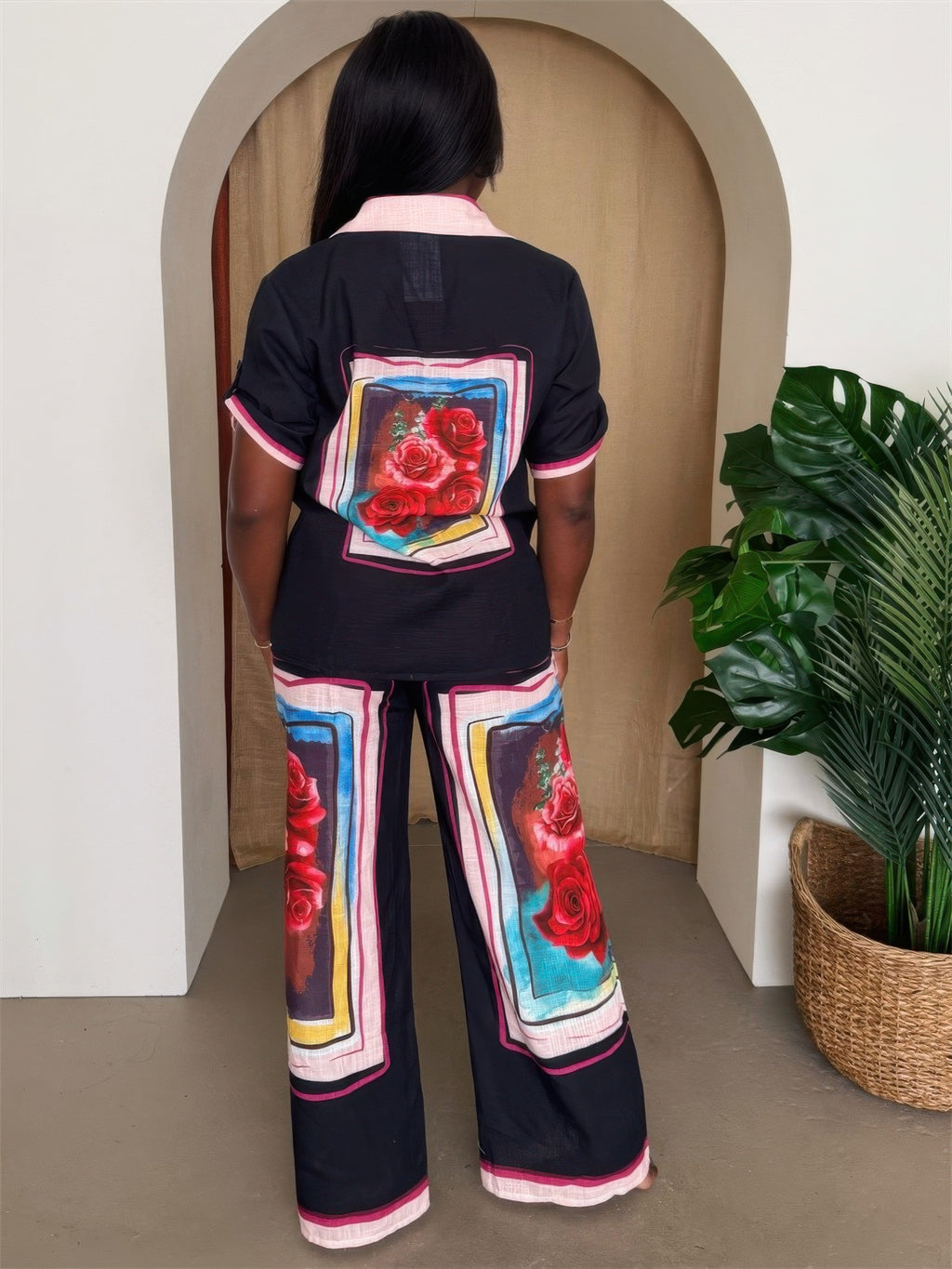 Back view: black resort set with framed rose panels on shirt and wide-leg trousers