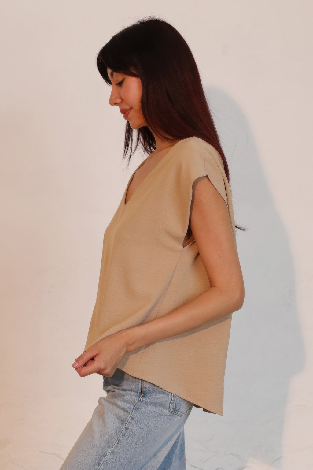 Tan loose V-neck crepe top with side drape and short sleeves.