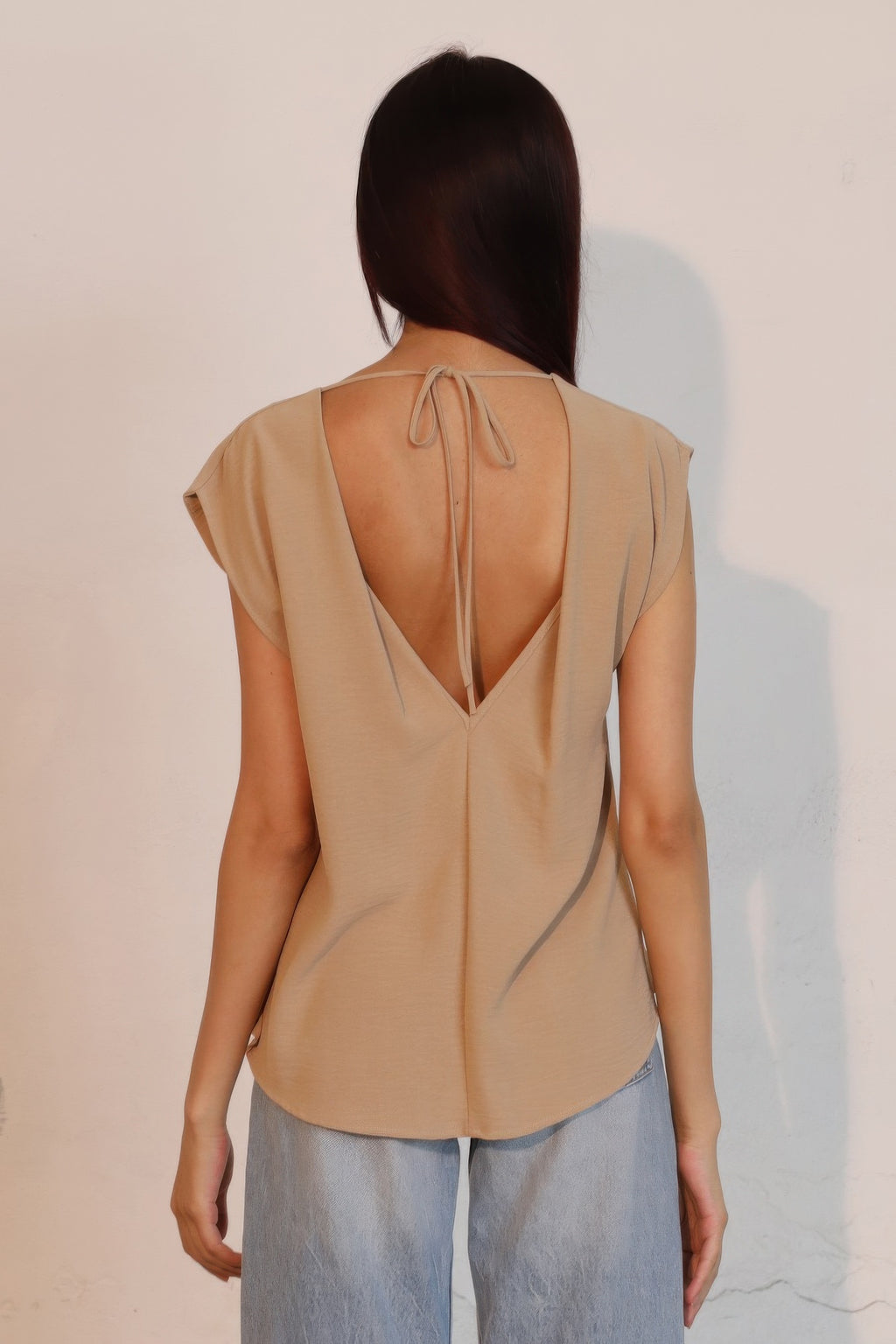 Tan low-back crepe top with open back and tied drawstrings.