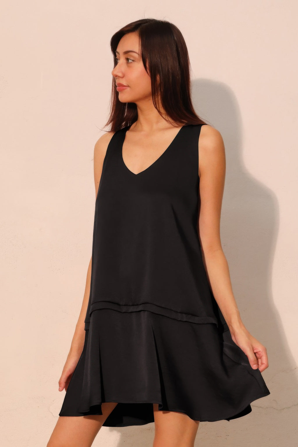 Black sleeveless V-neck swing dress with draped tiers and layered ruffle hem
