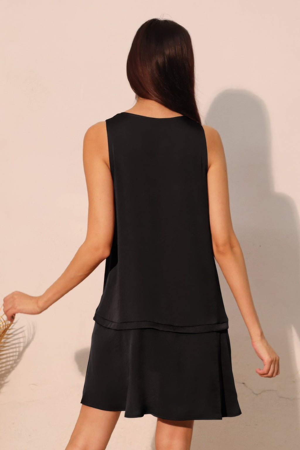 Back view of black sleeveless V-neck swing dress with tiered ruffle hem
