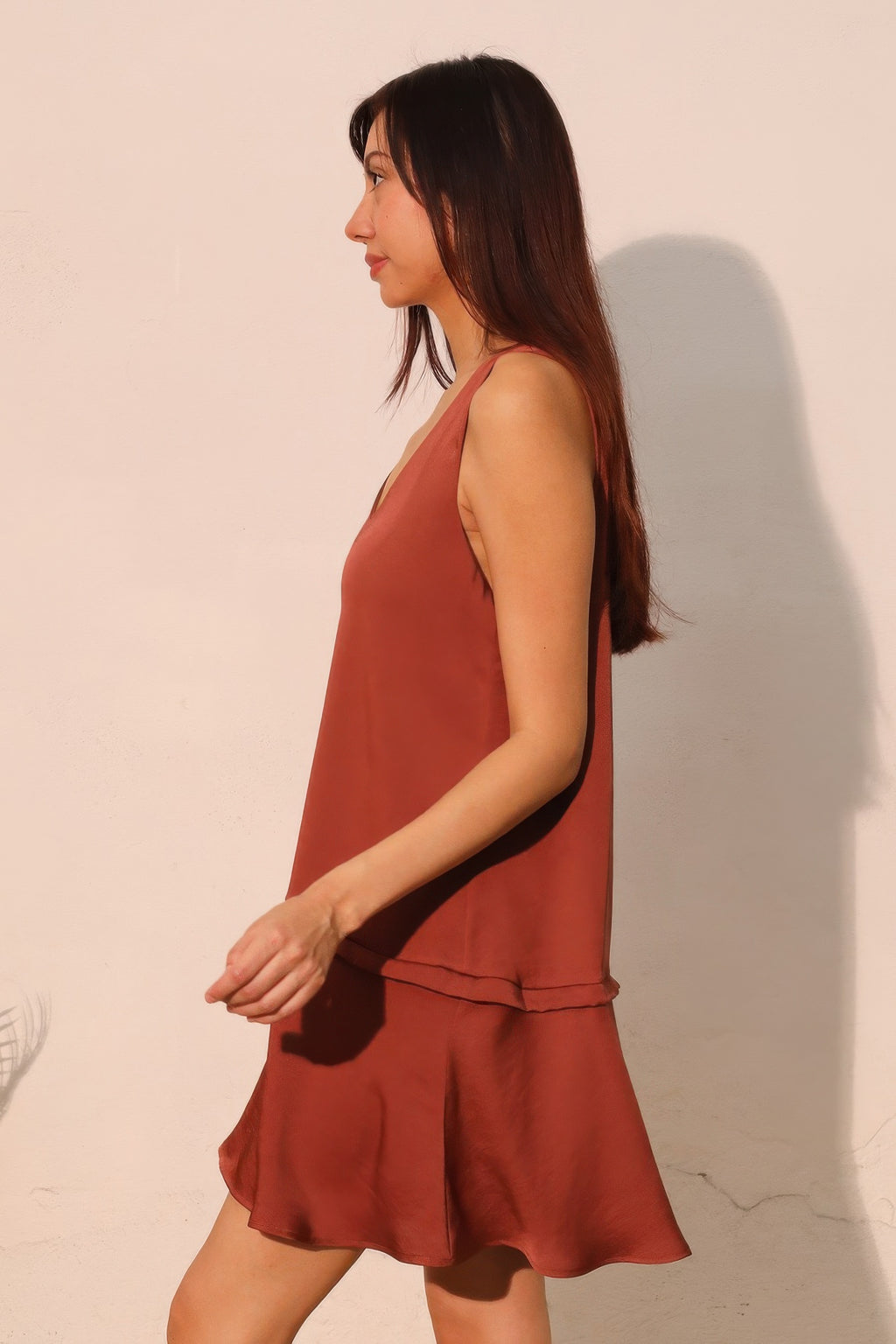 Brown sleeveless V-neck swing dress with layered hem and side-tie detail at waist