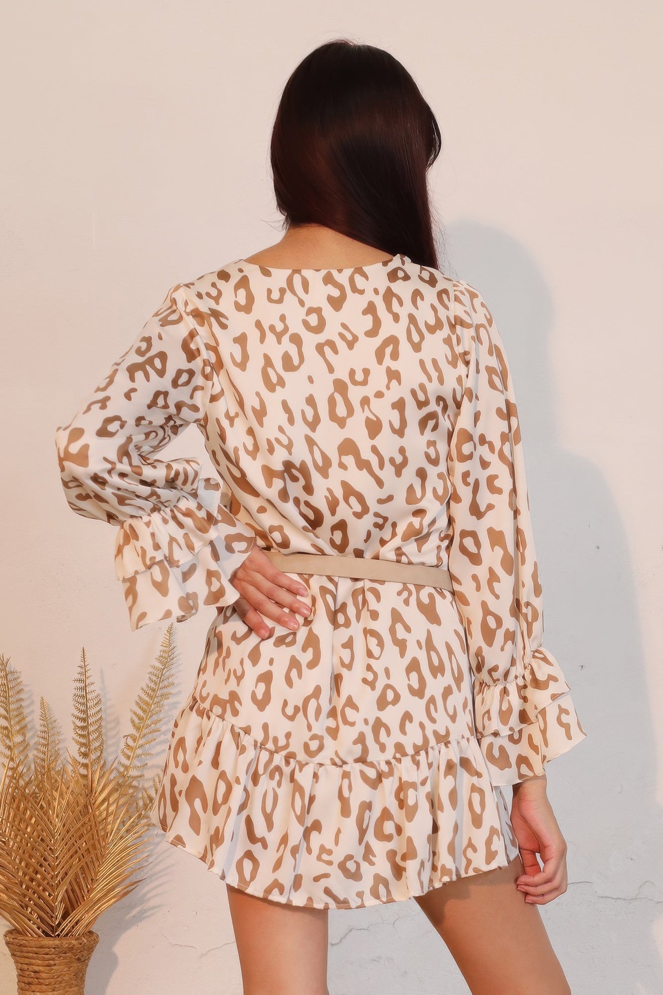 Back view of beige leopard mini dress with tiered skirt and belt tie at waist