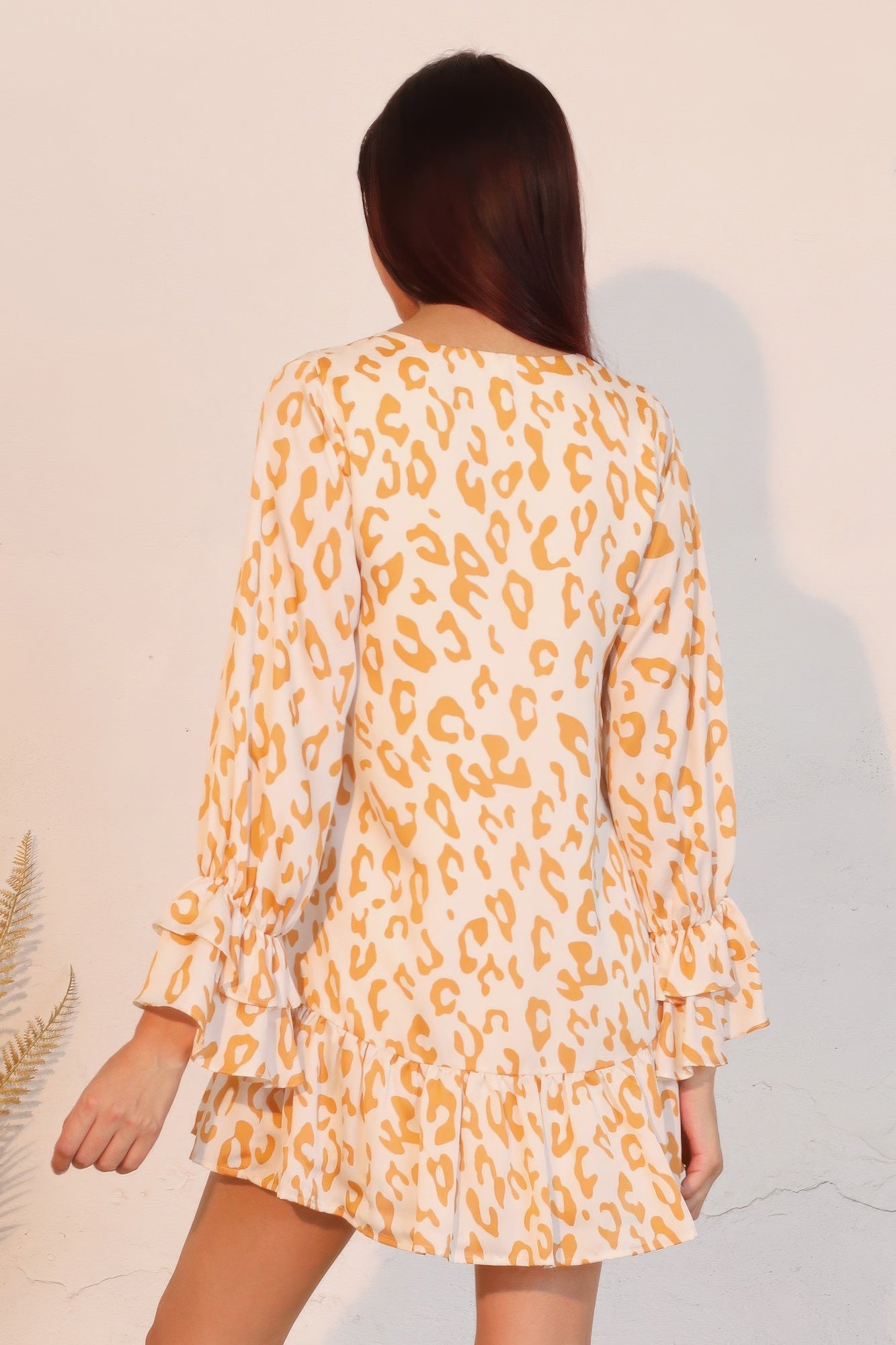 Back view: gold leopard mini dress with flowy long sleeves and tiered hem with ruffle cuffs