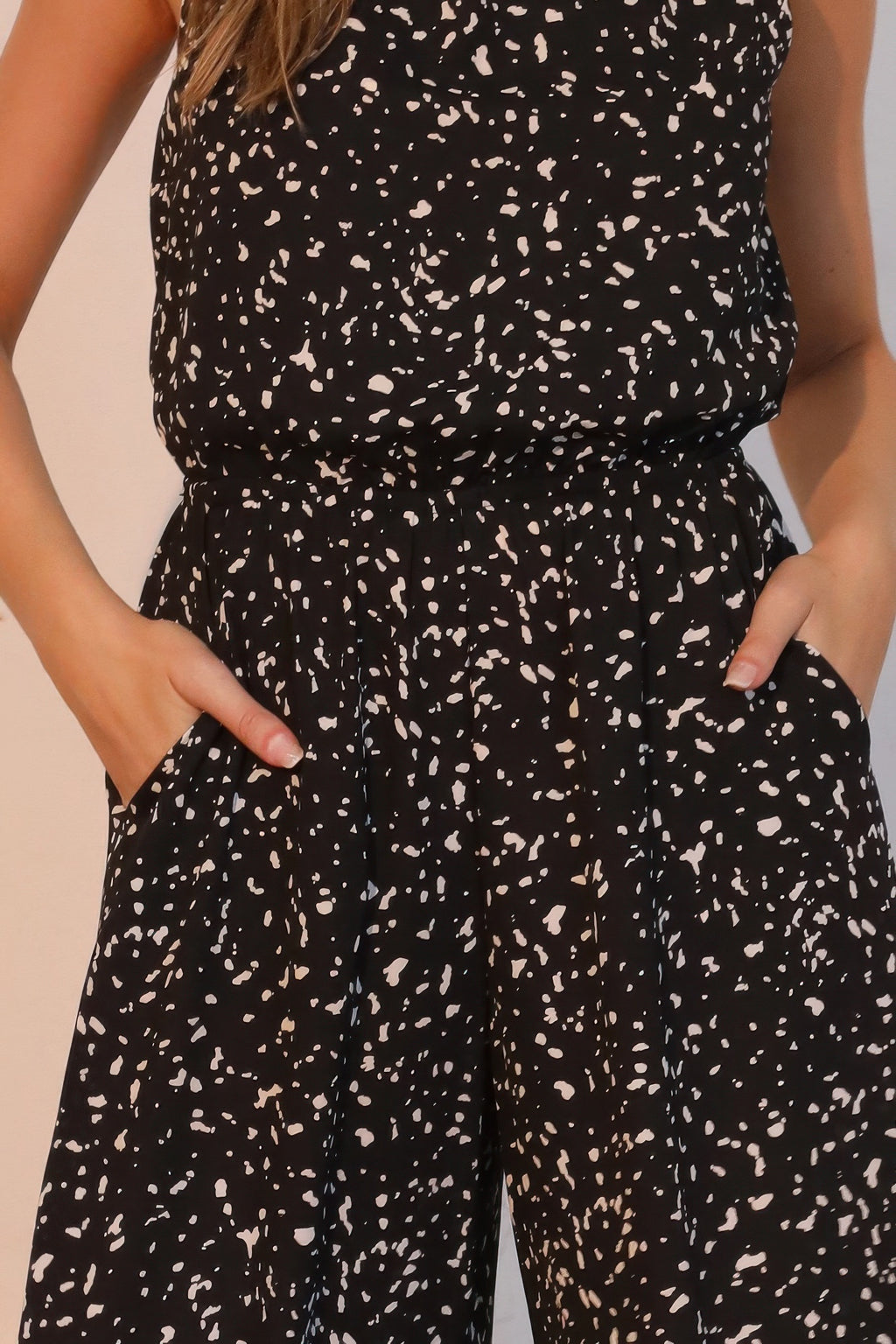 Close-up: black speckle jumpsuit bodice with gathered bubble waist, front pockets, sleeveless