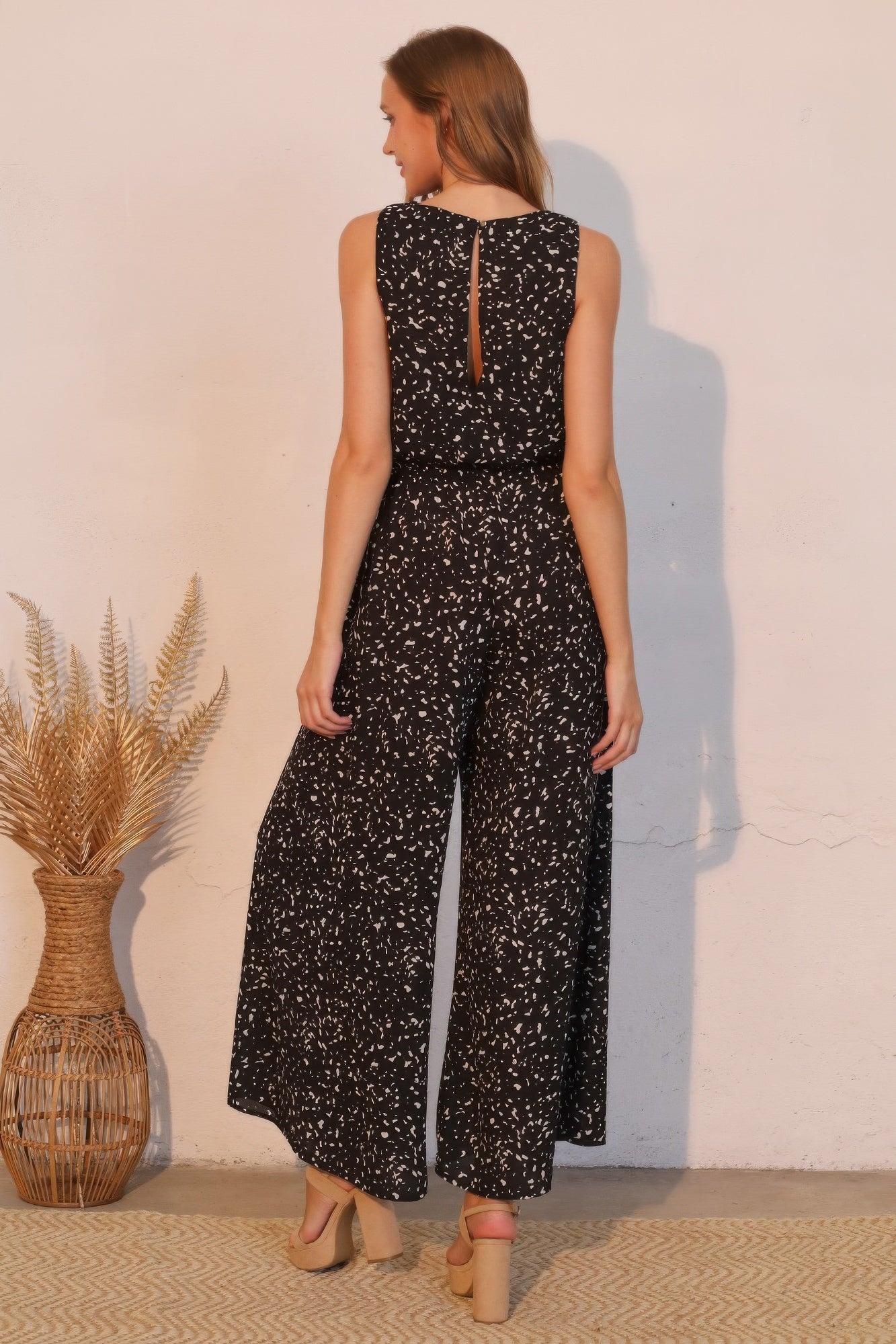 Back view: speckle sleeveless jumpsuit, black with white ink spots, open back, wide legs