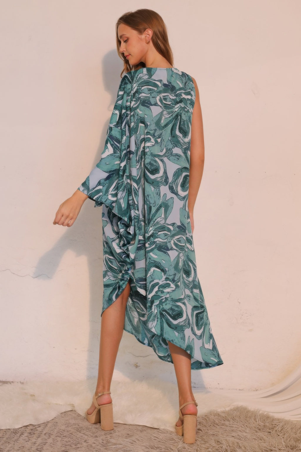 Petal print one-sleeve dress, teal, back-to-side angle with asym midi length