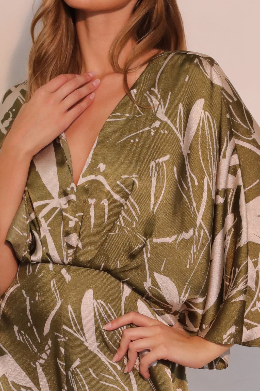 Close-up of olive satin jumpsuit neckline with V-slit and botanical print
