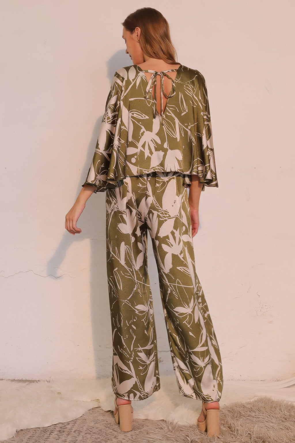 Back view of olive satin cape jumpsuit with tie-up detail and wide legs
