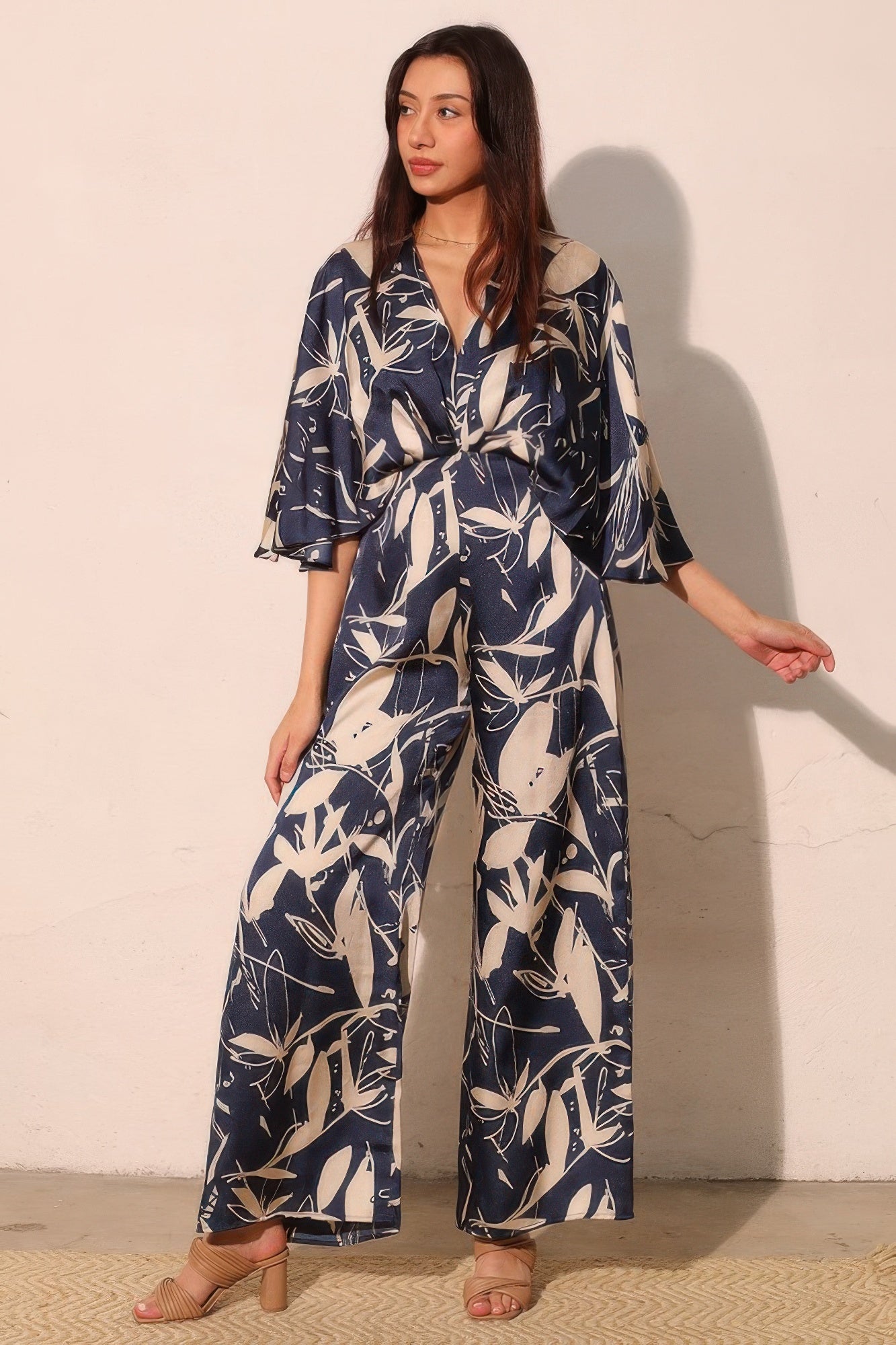 Navy satin cape jumpsuit with V-neck and botanical leaf print wide-leg pants