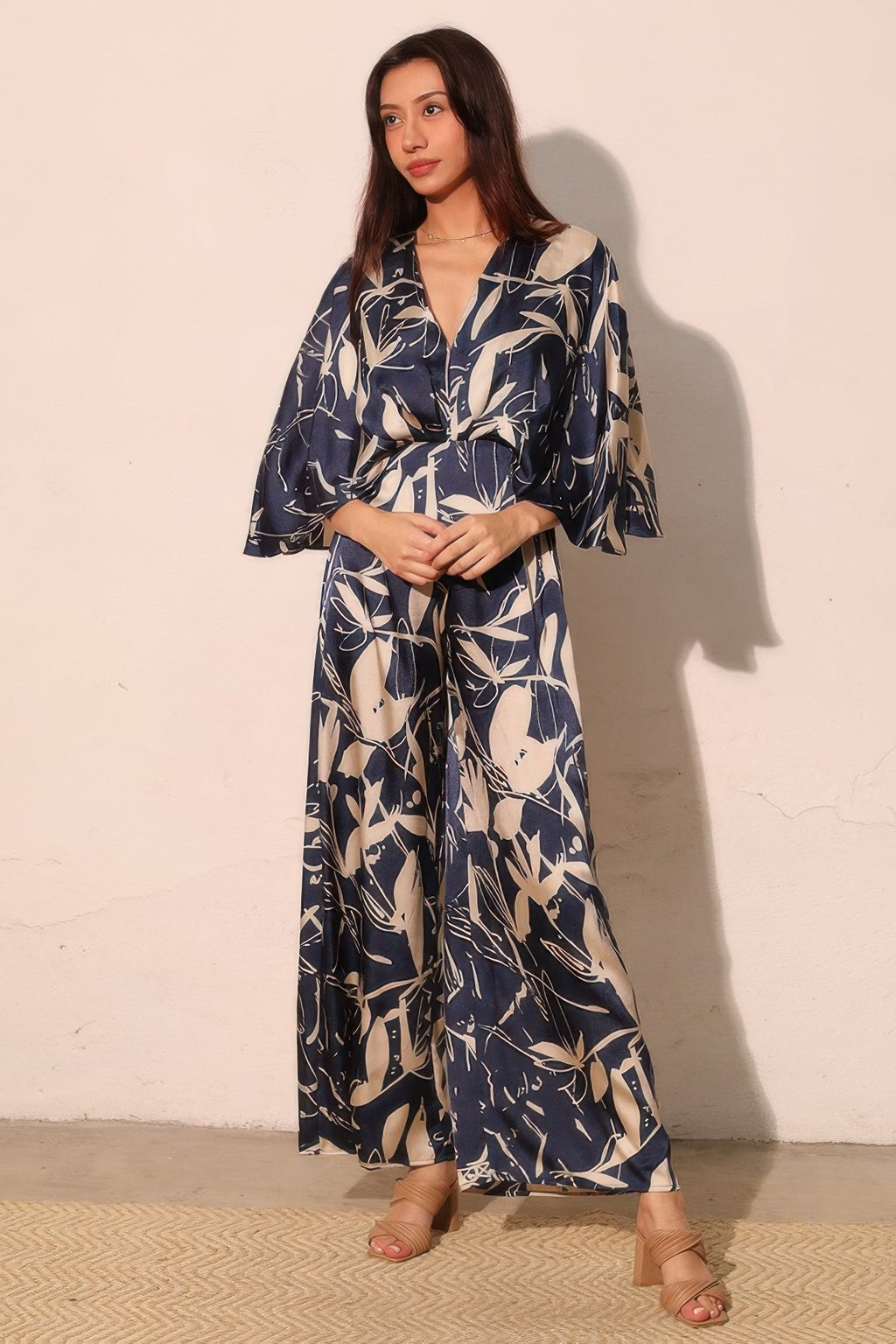 Navy satin jumpsuit with flutter cape sleeves, belted waist, and wide legs
