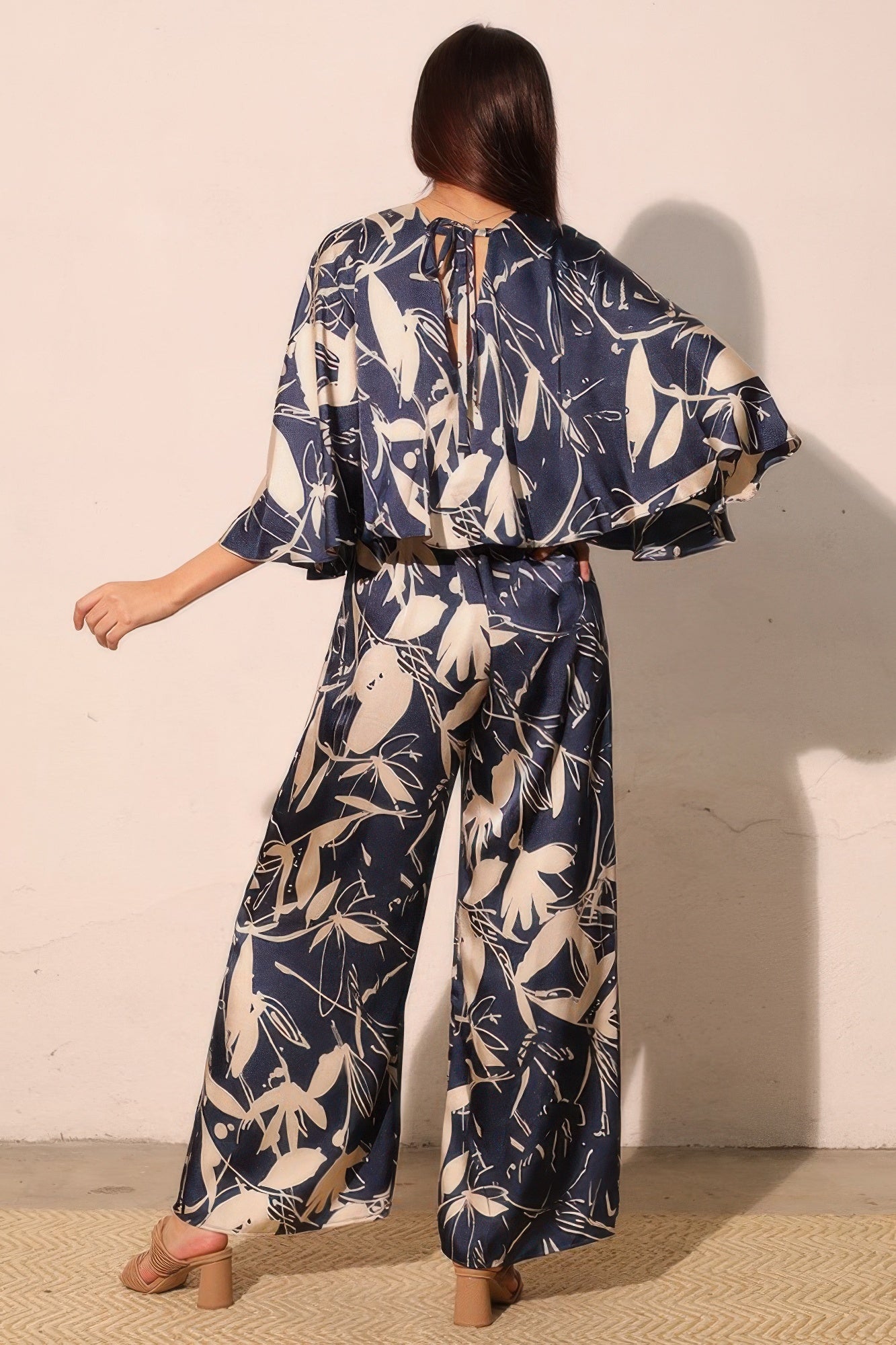 Back view of navy satin cape jumpsuit with tie at back and wide legs