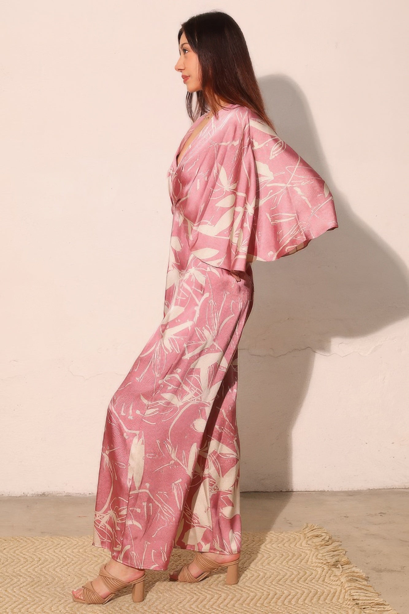 Pink satin wide-leg jumpsuit with flowing cape sleeve drape and floral print