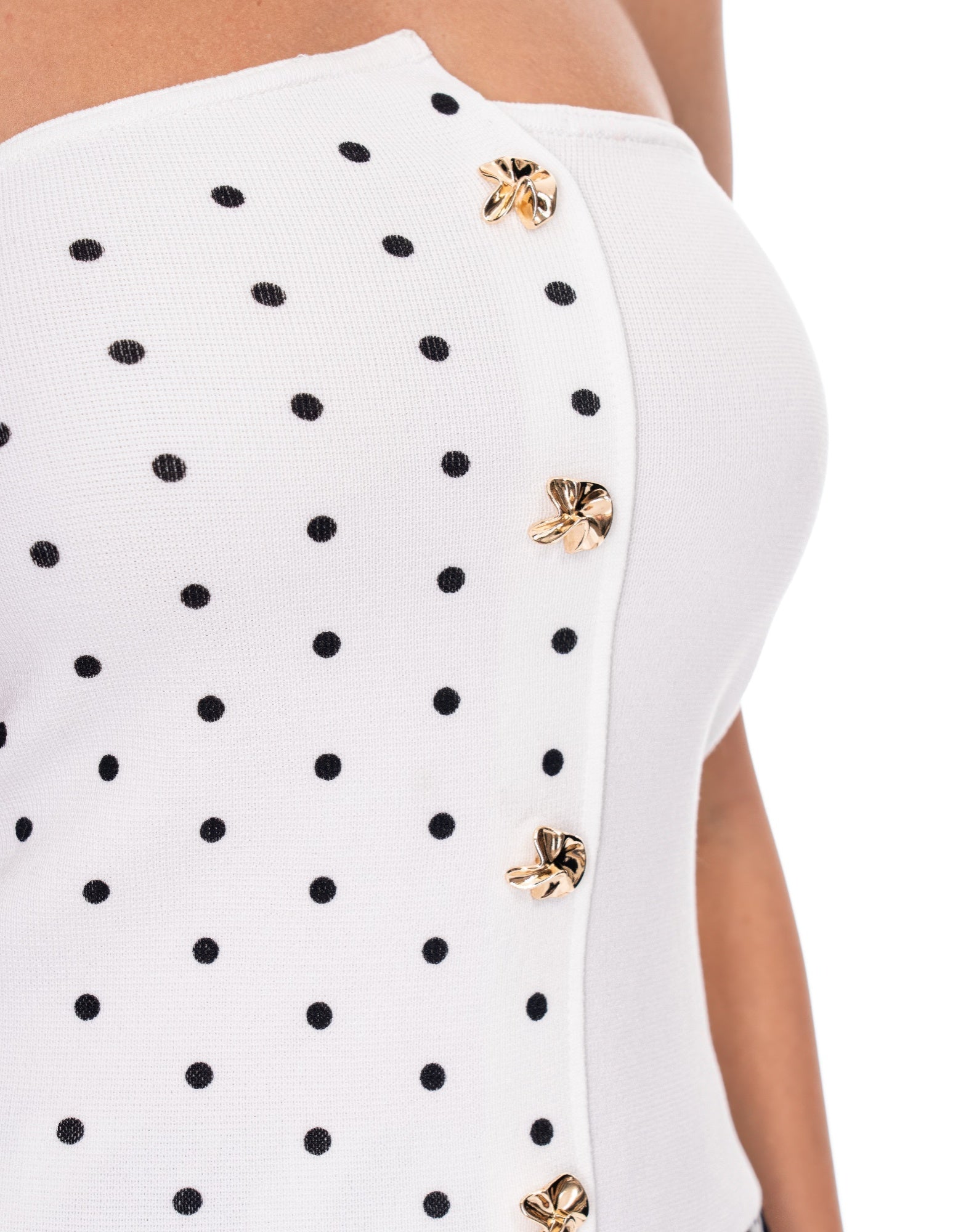 Close-up of white polka dot top with black dots and gold button embellishments