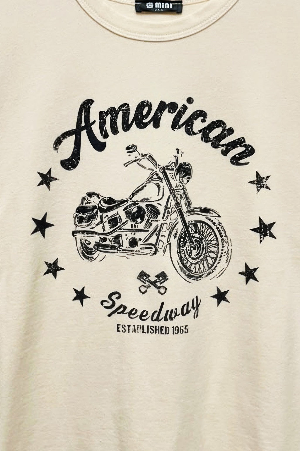 Cream T-shirt chest close-up: “American” script, motorcycle illustration and stars