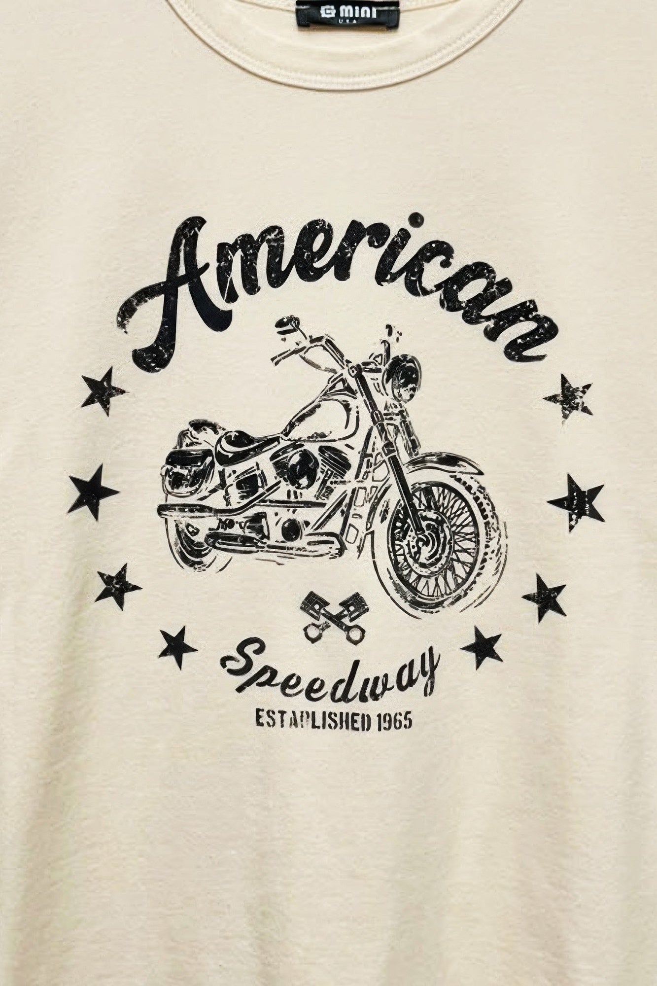 Cream T-shirt chest close-up: “American” script, motorcycle illustration and stars