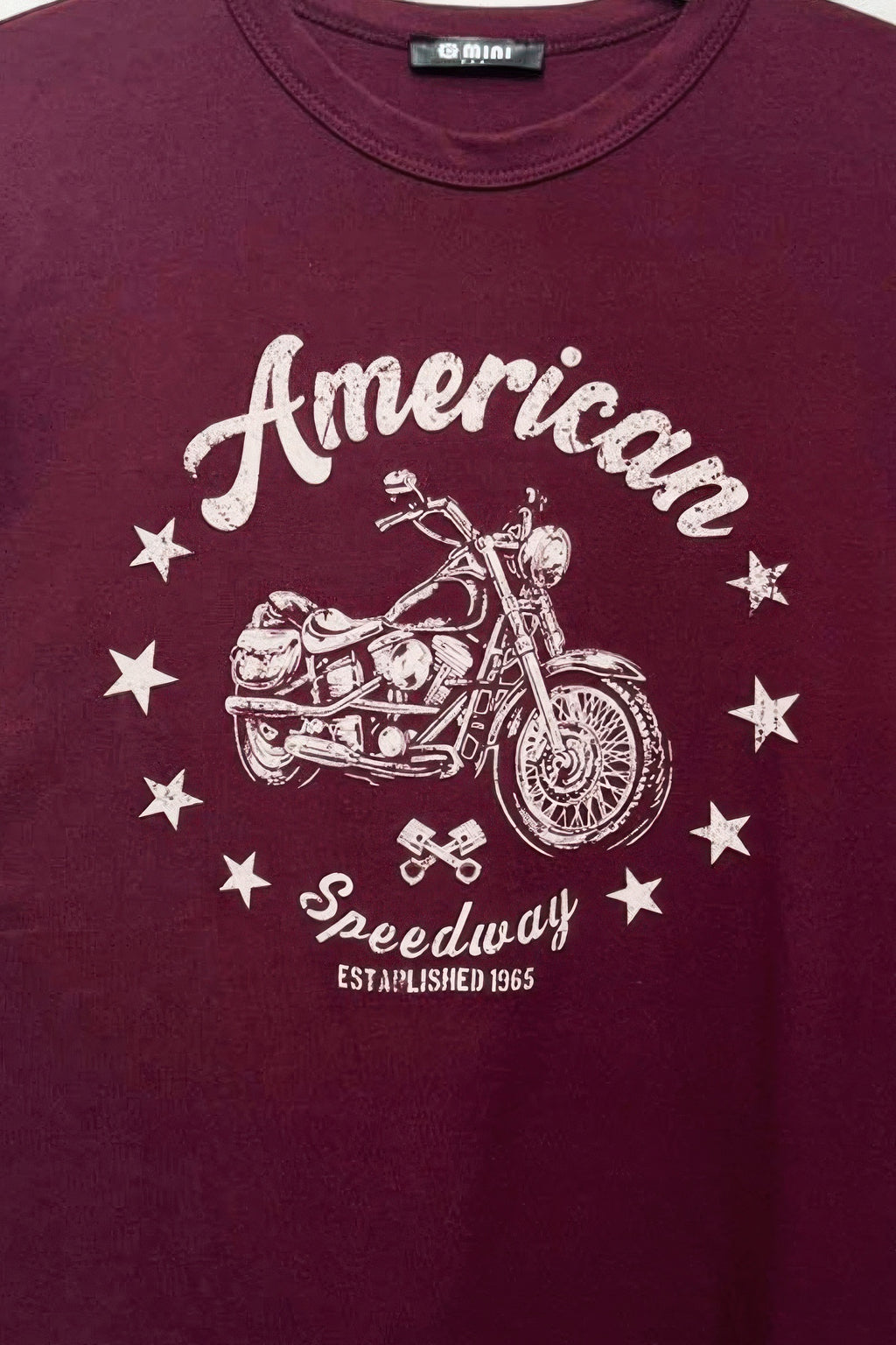 Burgundy tee close-up of “American” script with motorcycle and “Speedway” graphic