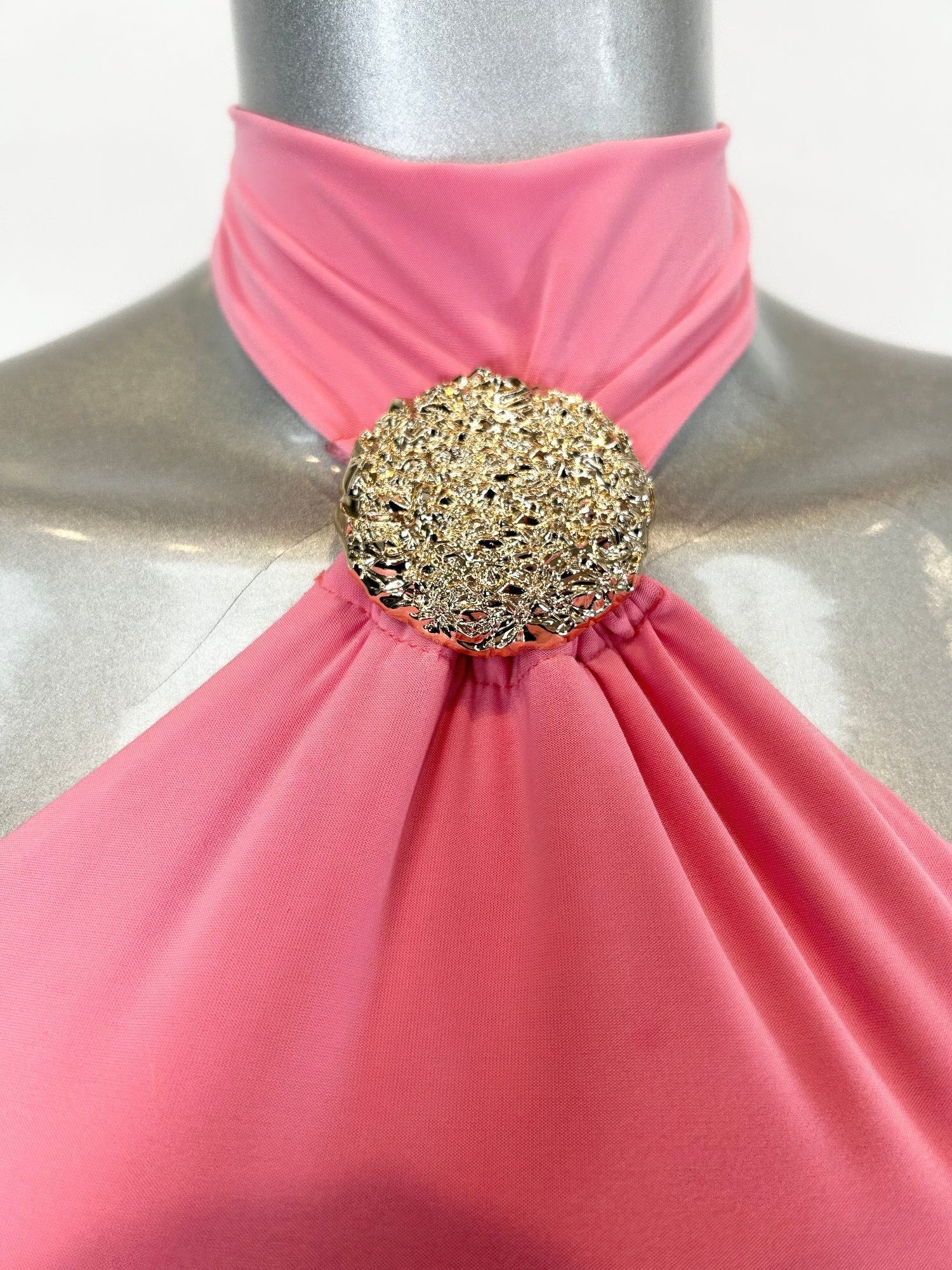 Close-up: bubble gum pink halter neckline with gold round jewel centerpiece