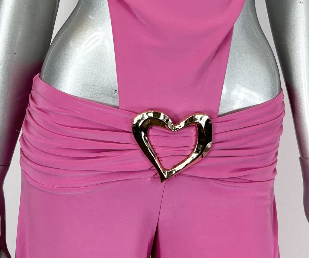 Nahaufnahme: Hot pink Jumpsuit mit großem goldfarbenem Herz-Gürtel