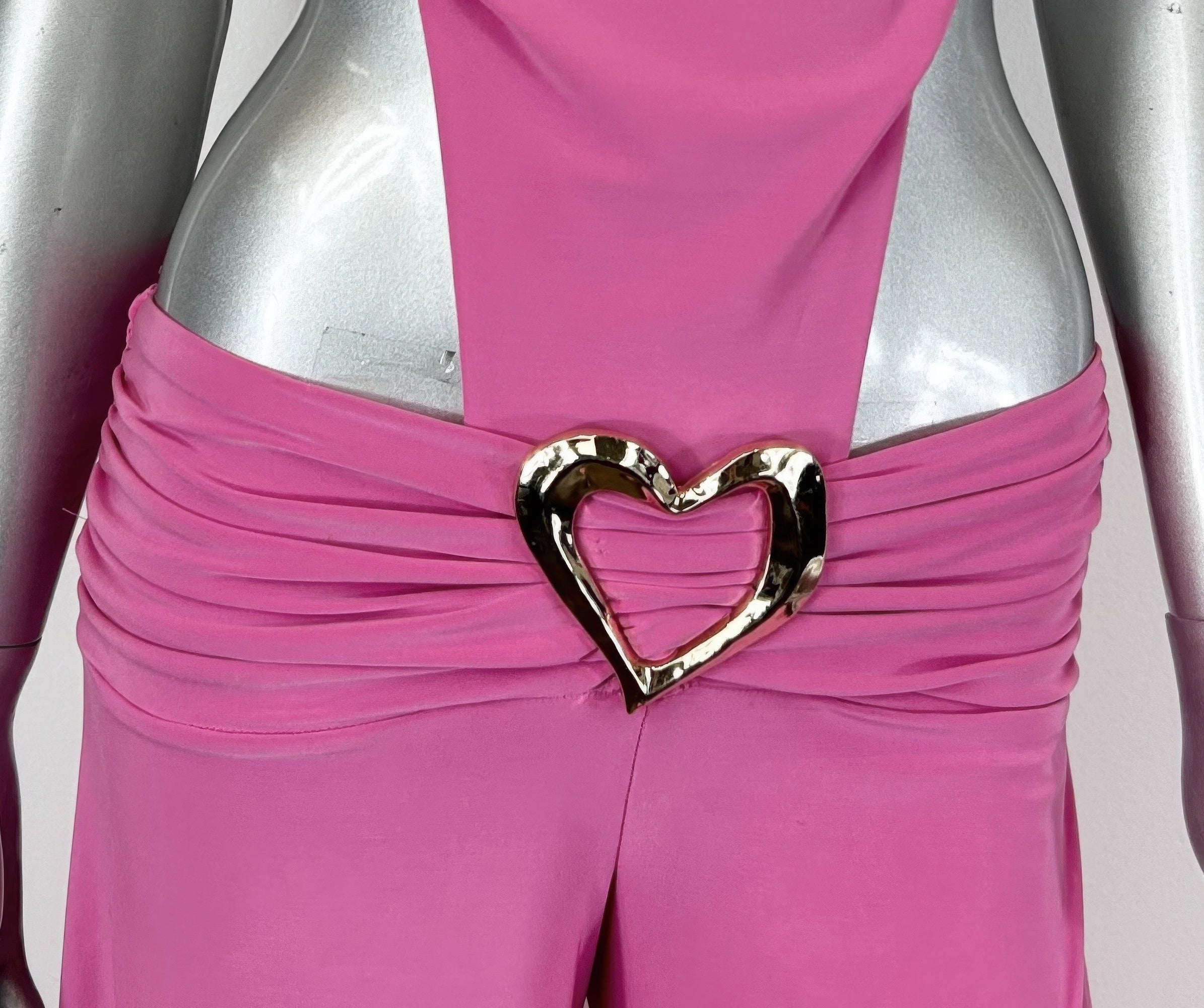 Nahaufnahme: Hot pink Jumpsuit mit großem goldfarbenem Herz-Gürtel