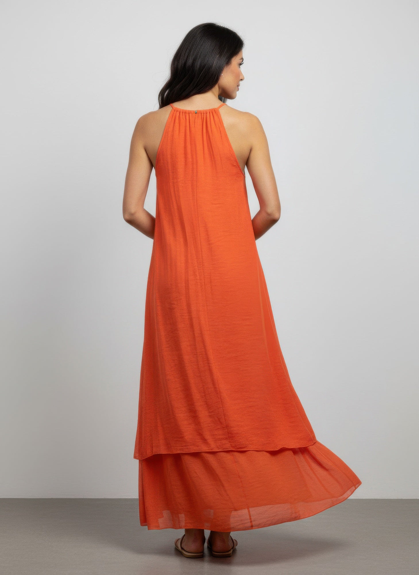 Back view orange sleeveless dress with gathered halter neckline and tiered hem
