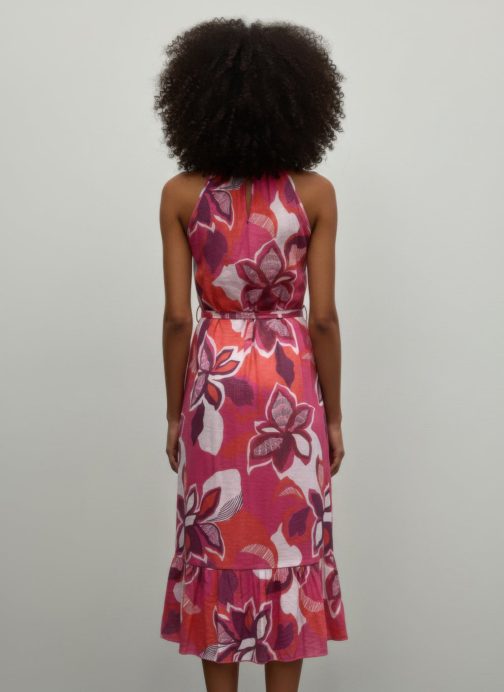 Back view of pink floral midi dress with halter straps and tied waist, tiered hem
