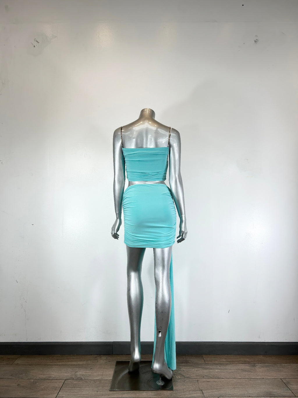 Mannequin view: aqua cropped bodice and ruched mini skirt with long trailing drape