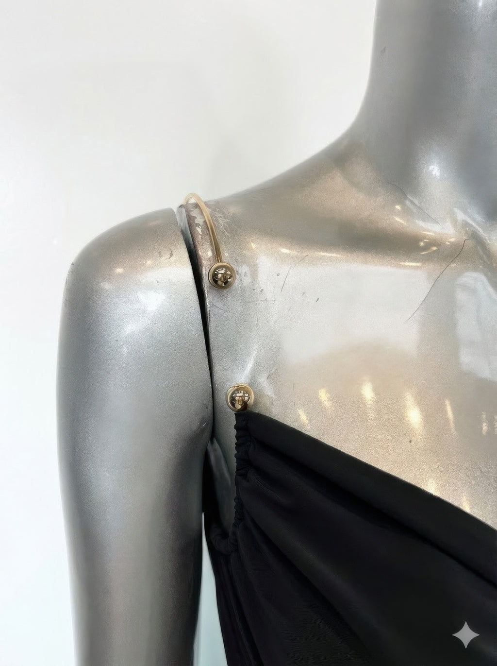 Back detail of black cowl-neck midi dress with metal hardware at straps and ruched drape