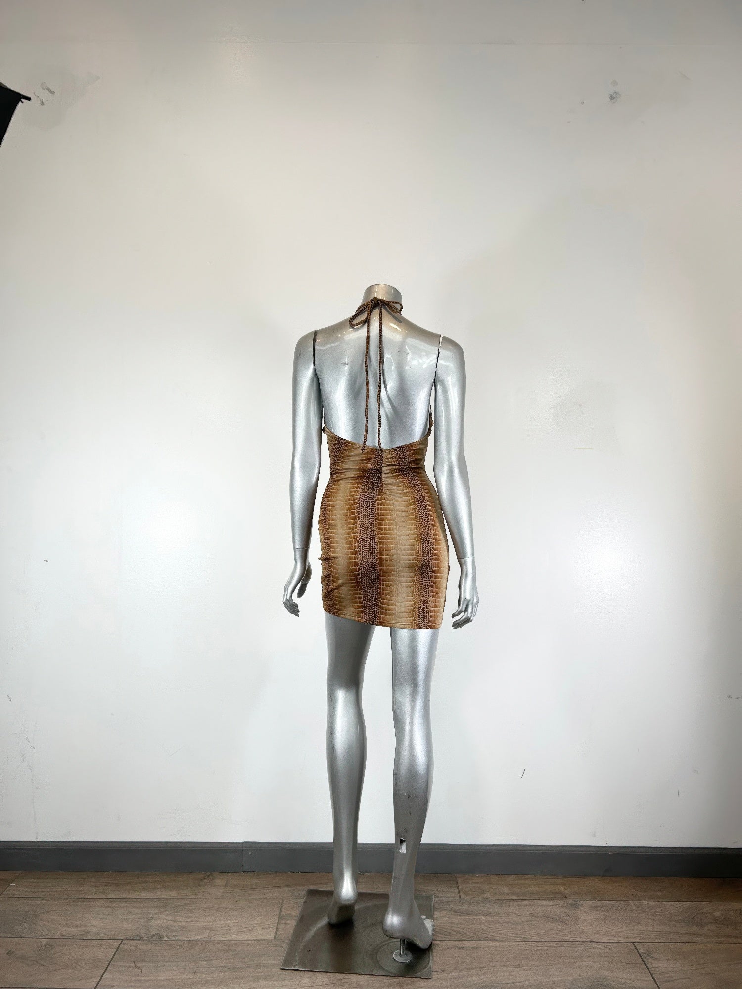 Back view of bronze/gold string neck mini dress with trim detail