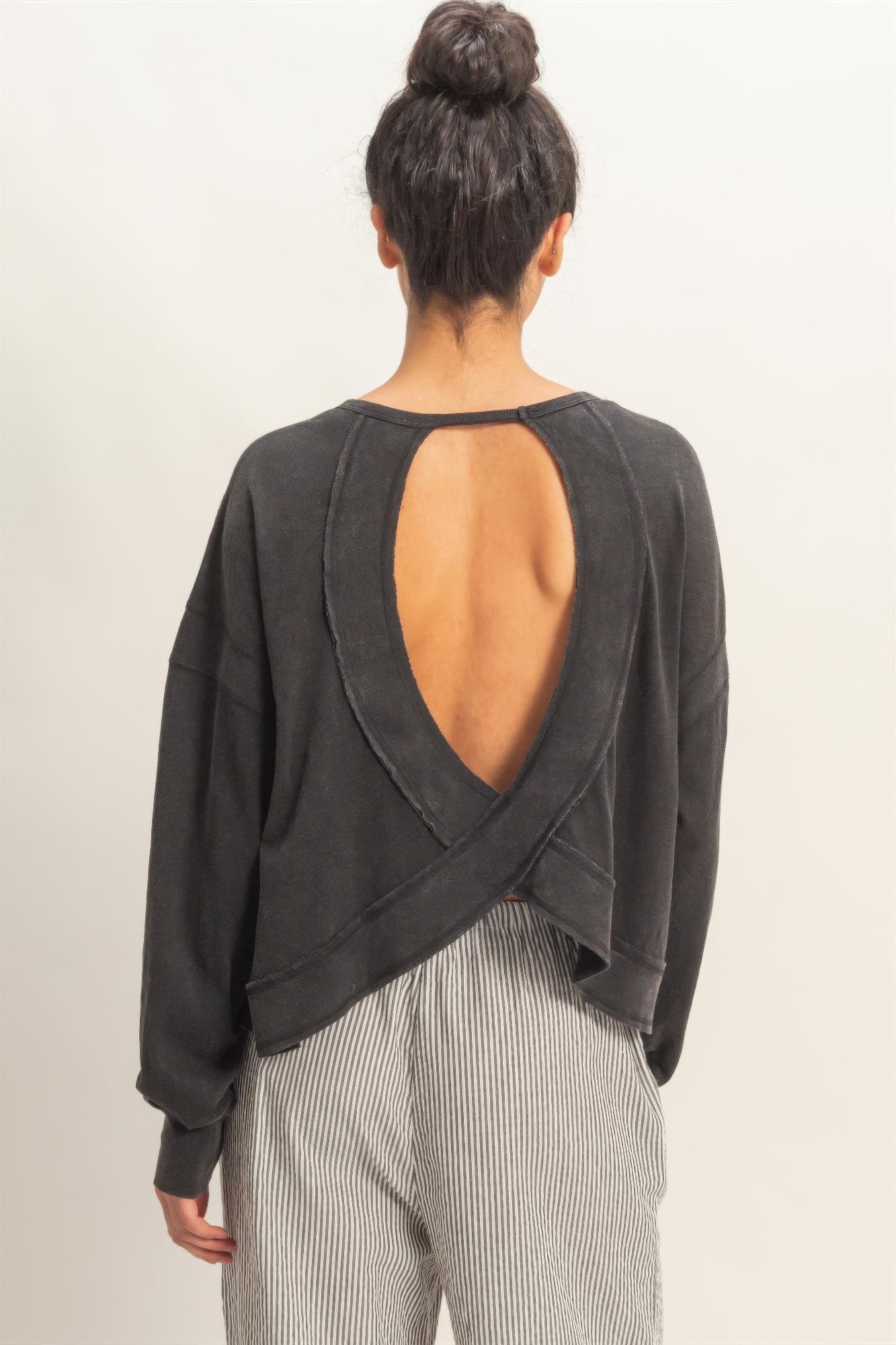 Black long-sleeve top from behind: deep open back with cross detail