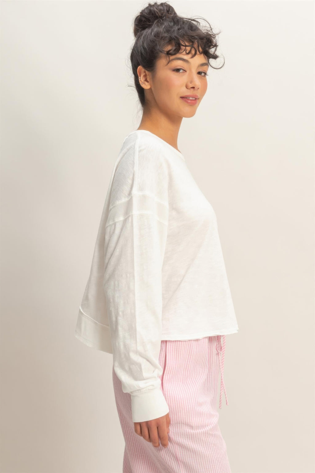 White long-sleeve top with flowy side drape and open-back cross detail