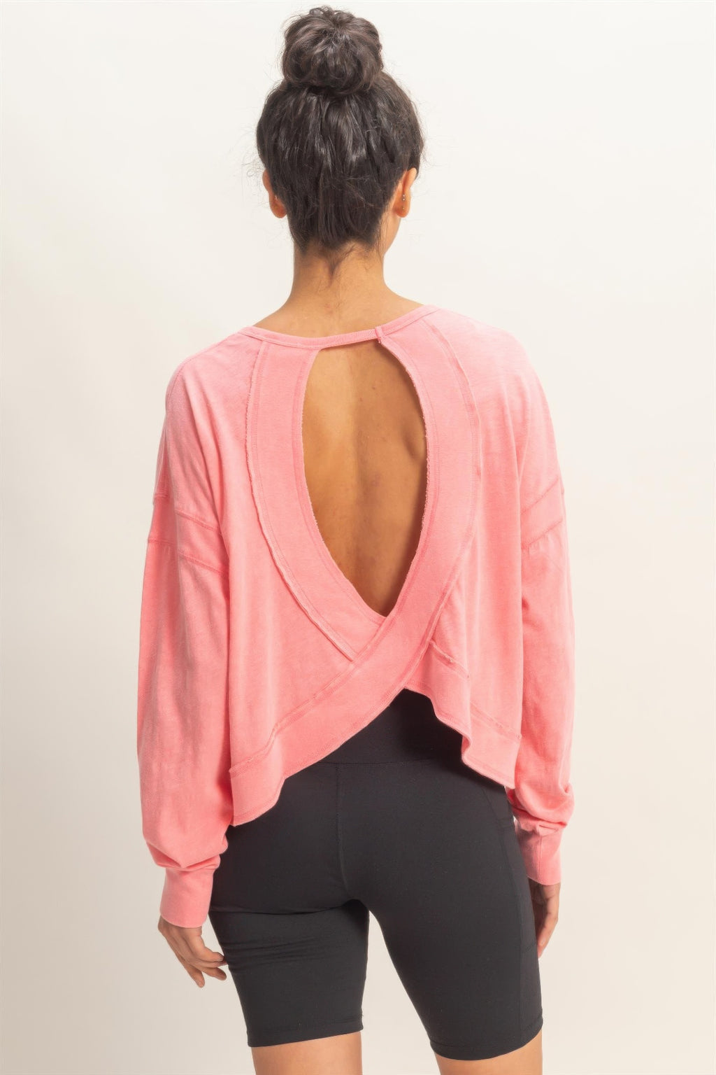 Back view of taffy pink open-back long-sleeve top with crisscross seam detail