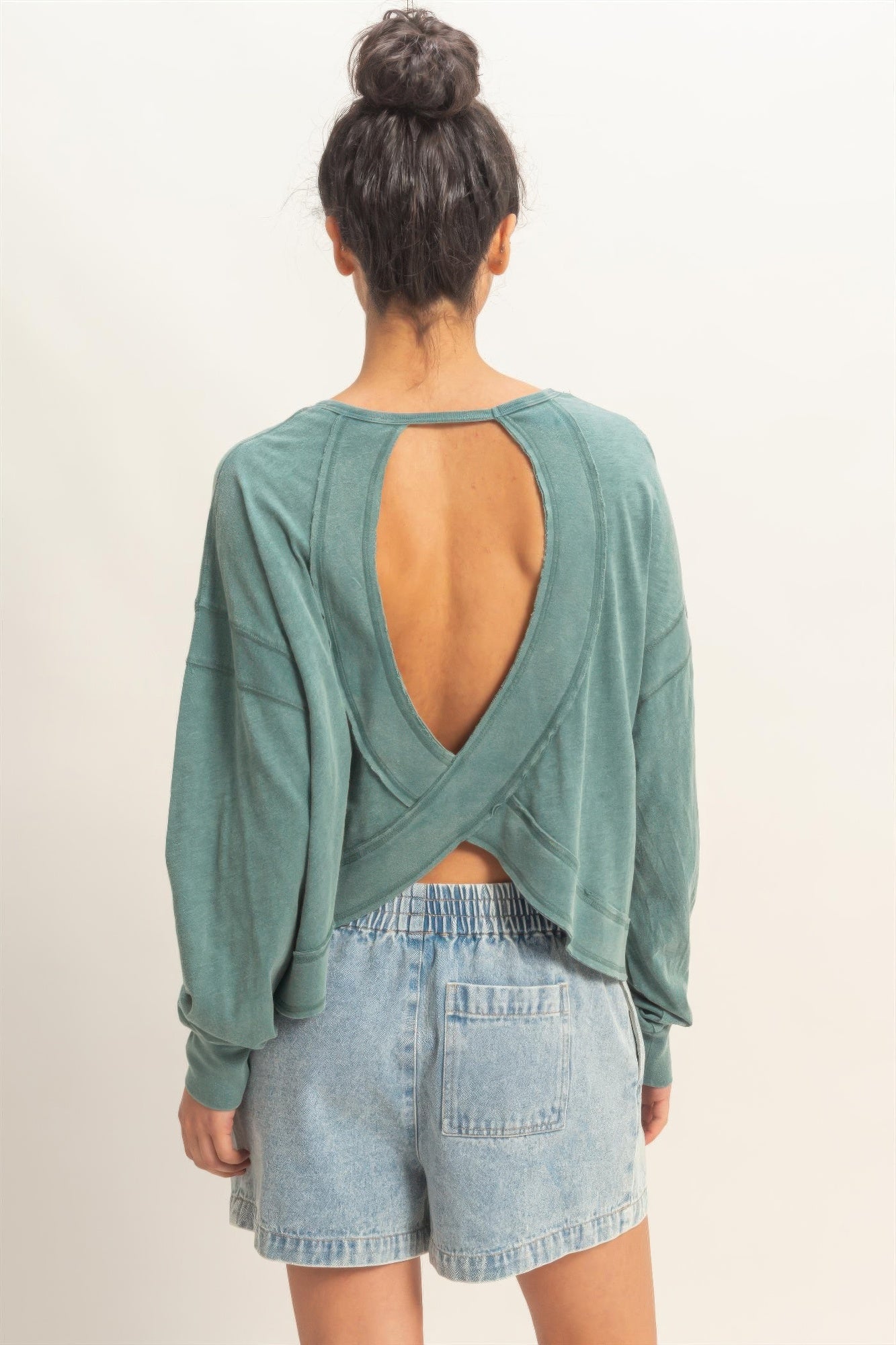 Open-back cross detail on long-sleeve top, dark teal back view