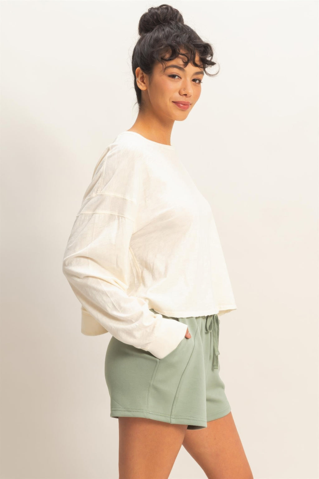 White long-sleeve top on an open back with crisscross strap detail, flowing drape