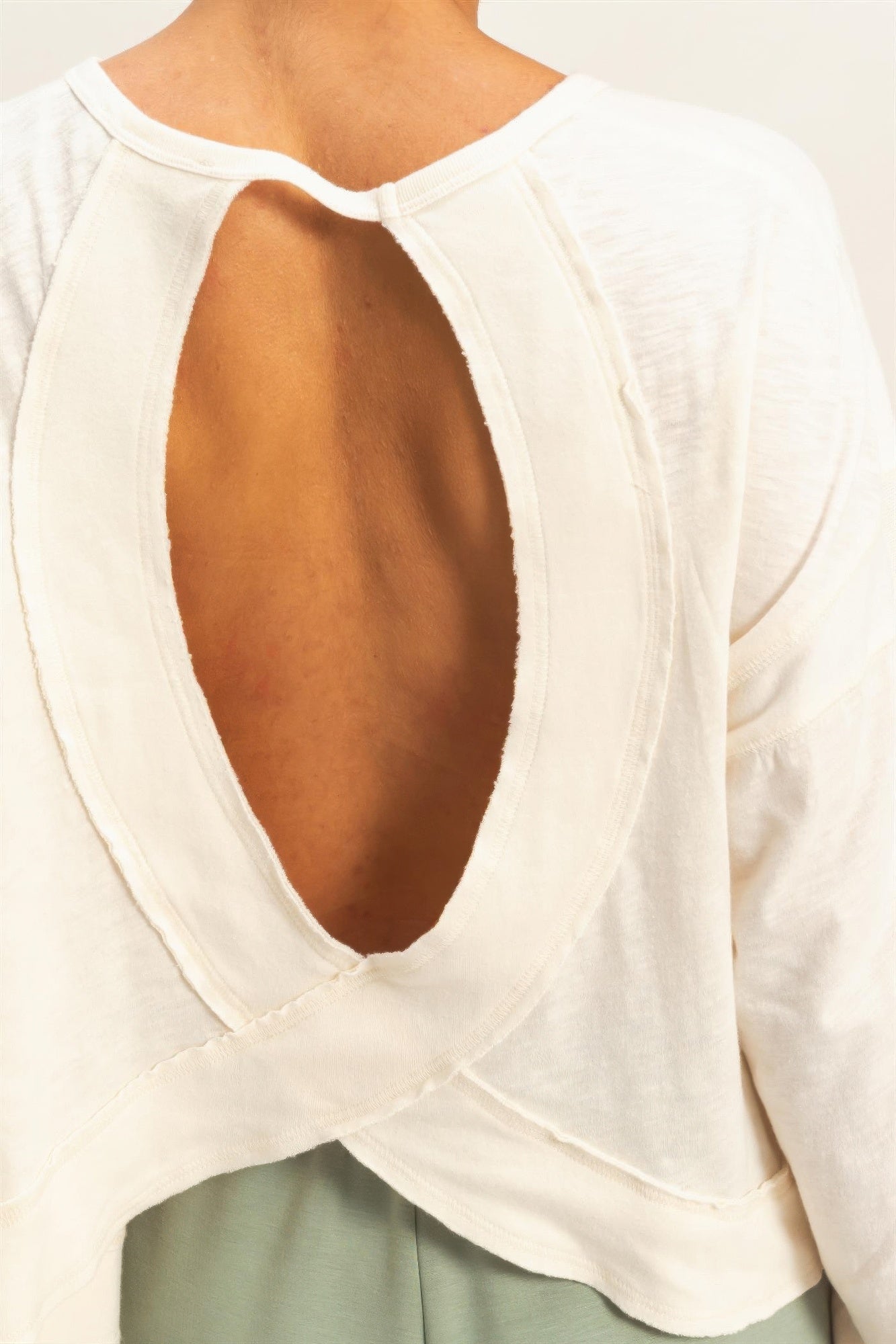 Close-up of white open-back long-sleeve top with oval cutout and crisscross neckline