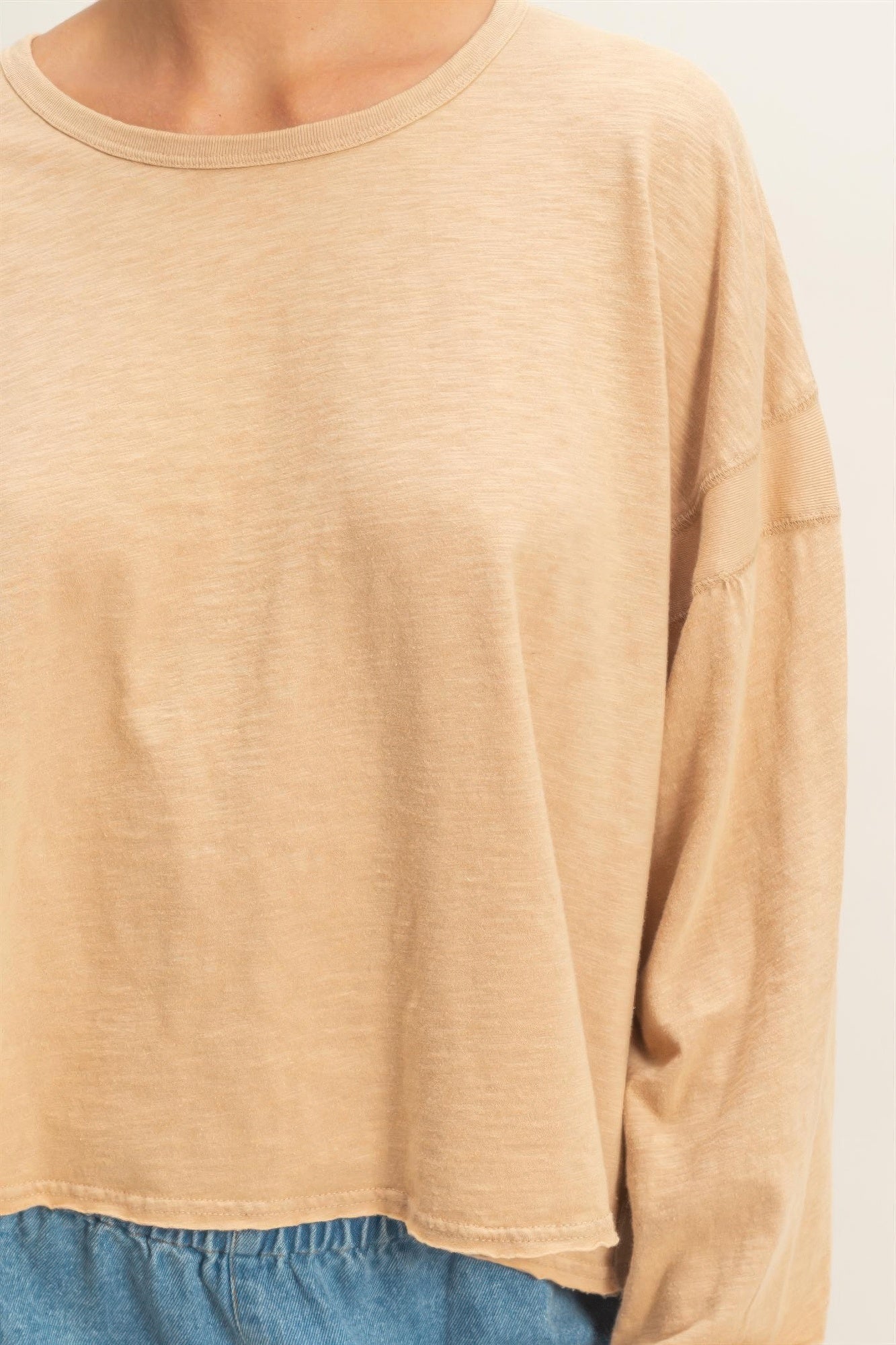 Dark taupe long-sleeve top with crew neck and smooth jersey-like fabric texture