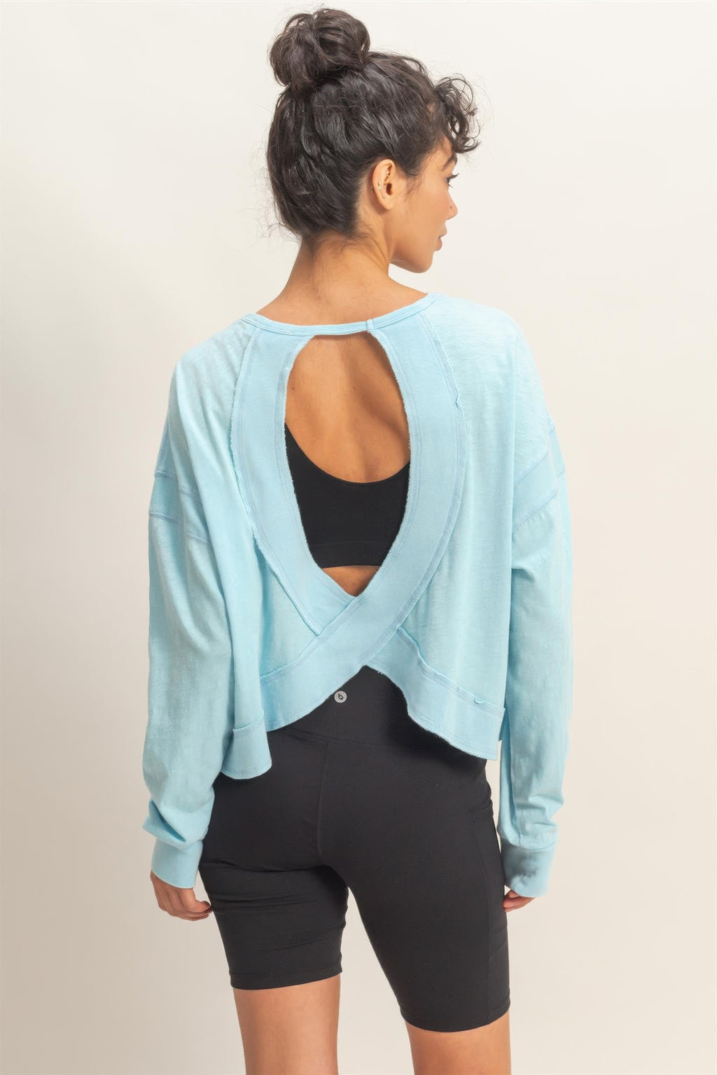 Open-back cross detail on light blue long-sleeve top, back neckline