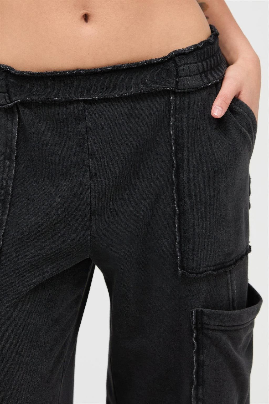 Black cargo pants close-up: elastic waistband and stitched pocket details